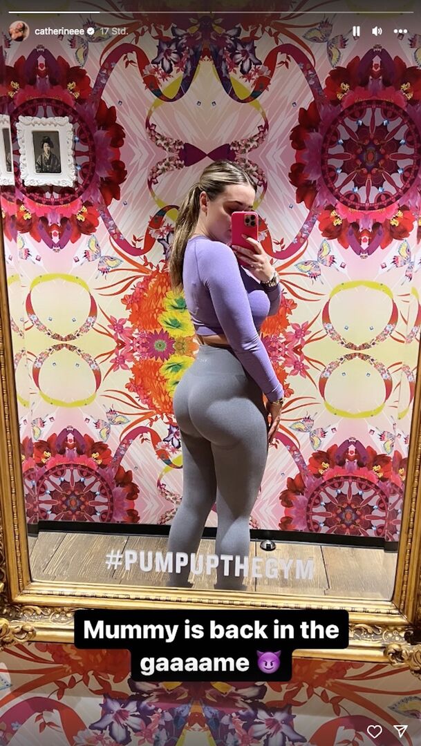 Cathy Lugner steht vor einer bunten Wand. Sie trägt Sportkleidung und posiert vor einem Spiegel im Fitness Center.