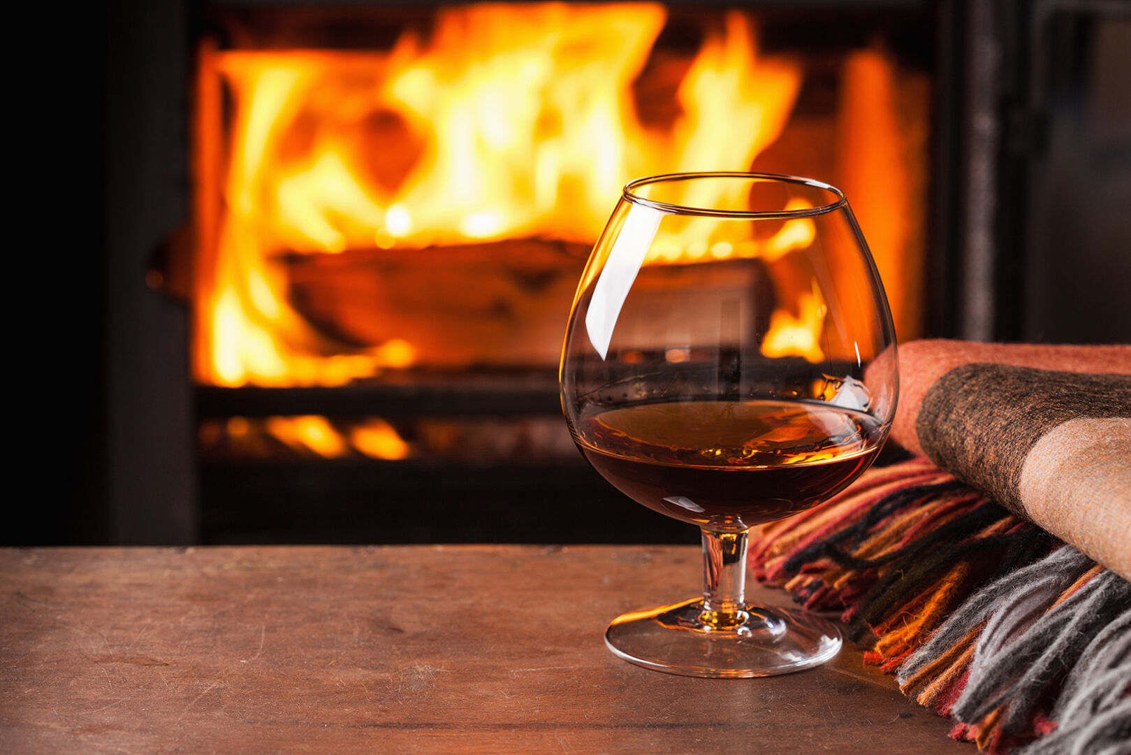 Ein Glas Whisky steht vor dem Kamin | Credit: iStock.com/OlgaMiltsova