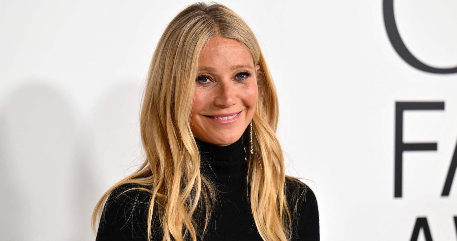 Gwyneth Paltrow trägt einen schwarzen Rollkragenpullover und offene blonde Haare.
