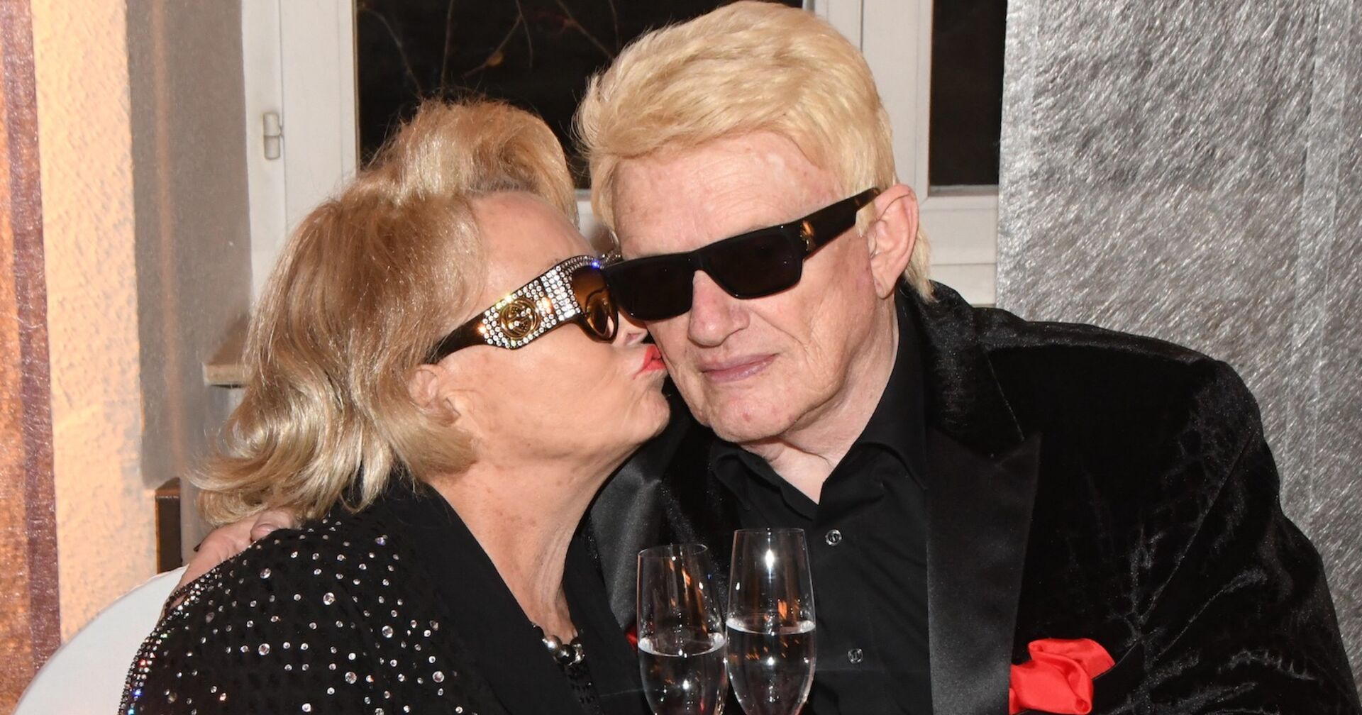 Hannelore küsst Heino zärtlich auf die Wange. Beide tragen dunkle Sonnenbrillen, das ist sein Markenzeichen.