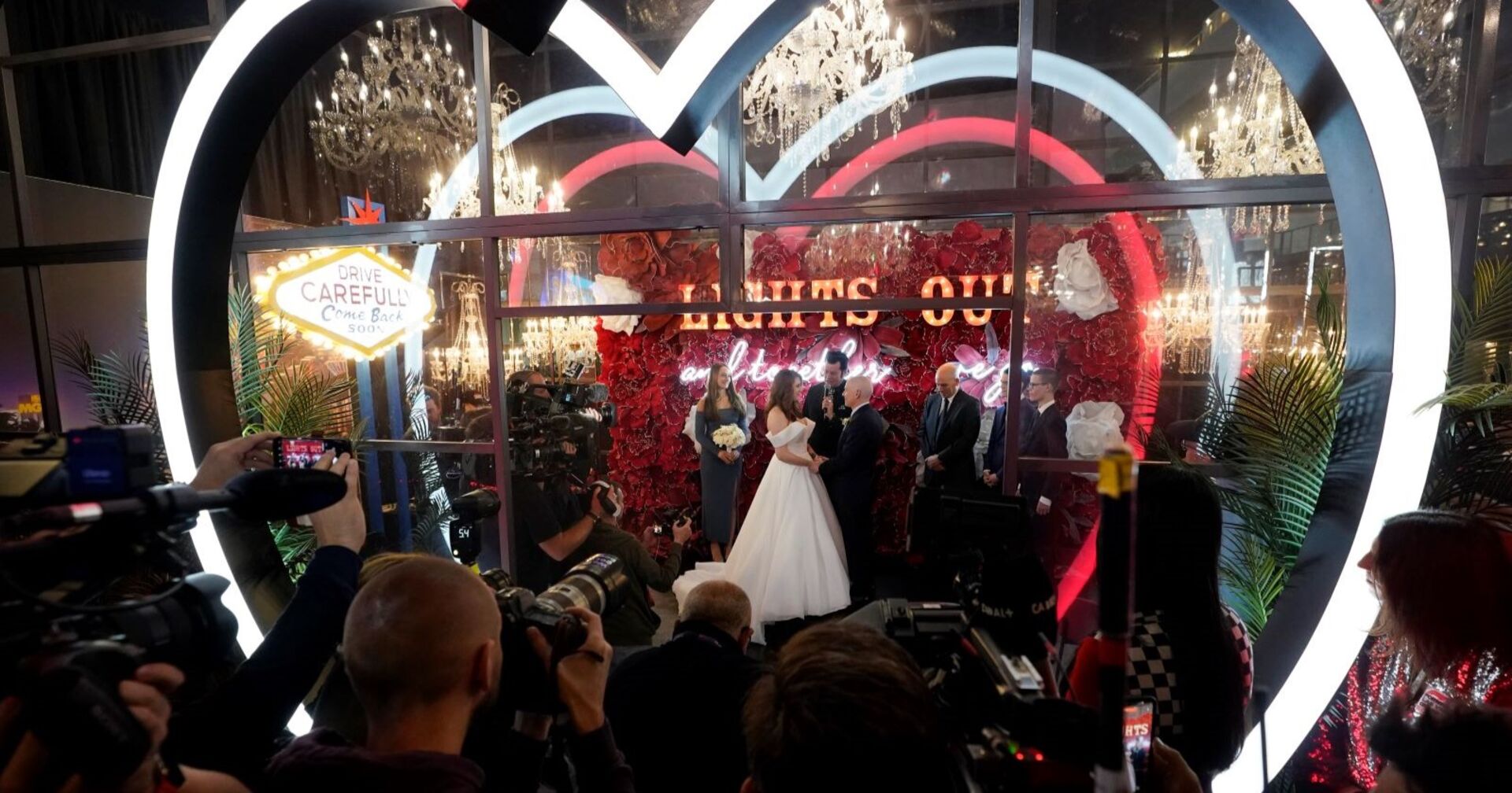 Ein Brautpaar unter LED-Lichterherzen vor jeder Menge Fotografen