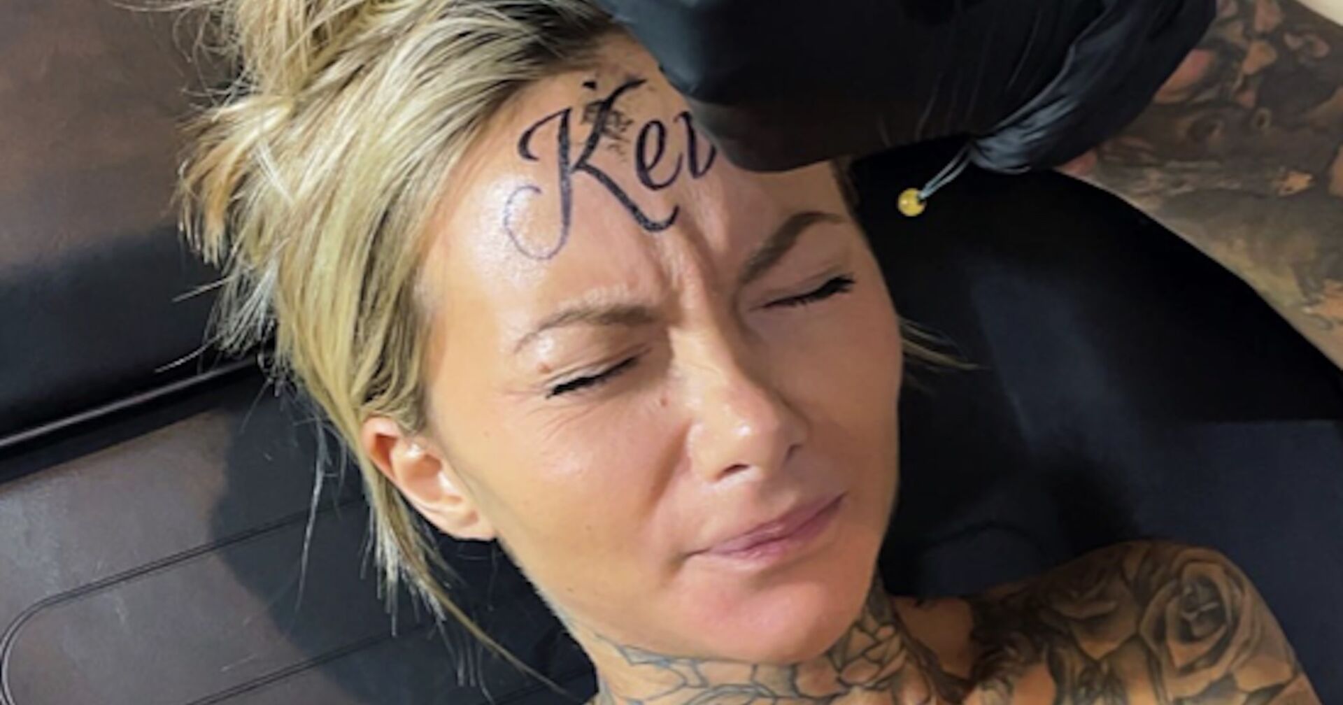 Eine Frau mit blonden Haaren lässt sich &quot;Kevin&quot; auf ihre Stirn tätowieren.