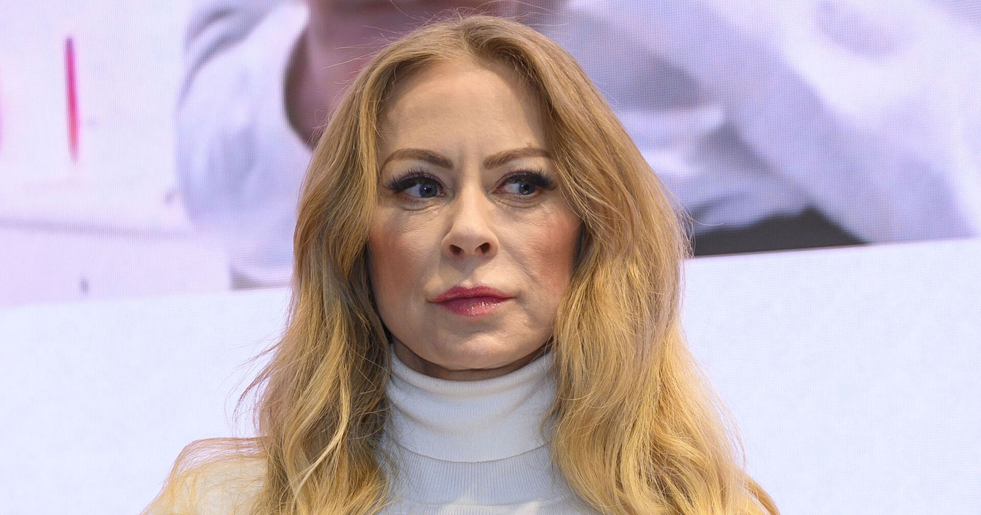 Jenny Elvers trägt einen weißen Rollkragenpulli und offene blonde, lange Haare.