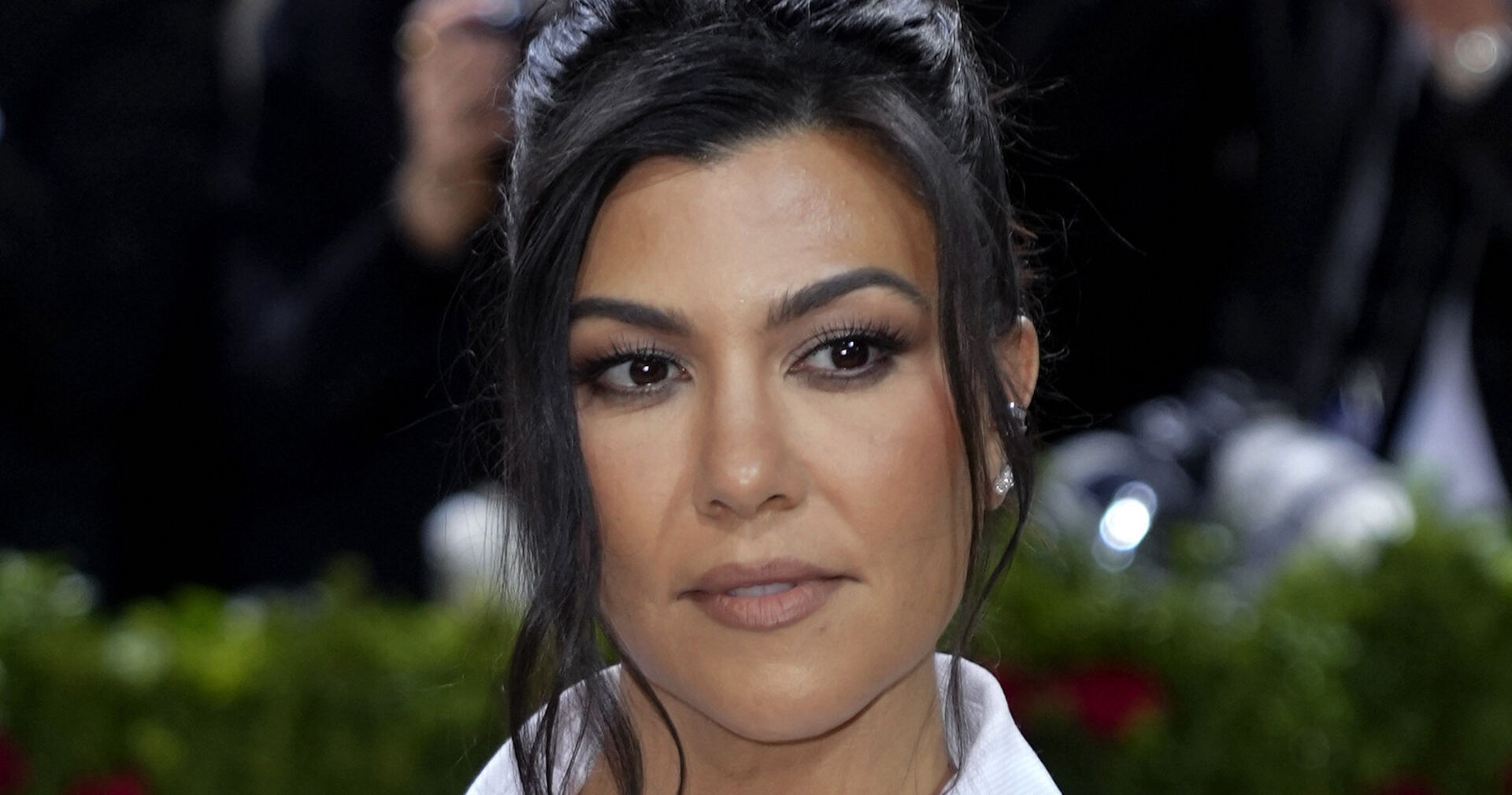 Kourtney Kardashian trägt hochgeschlossene schwarze Haare. Sie steht auf dem roten Teppich.