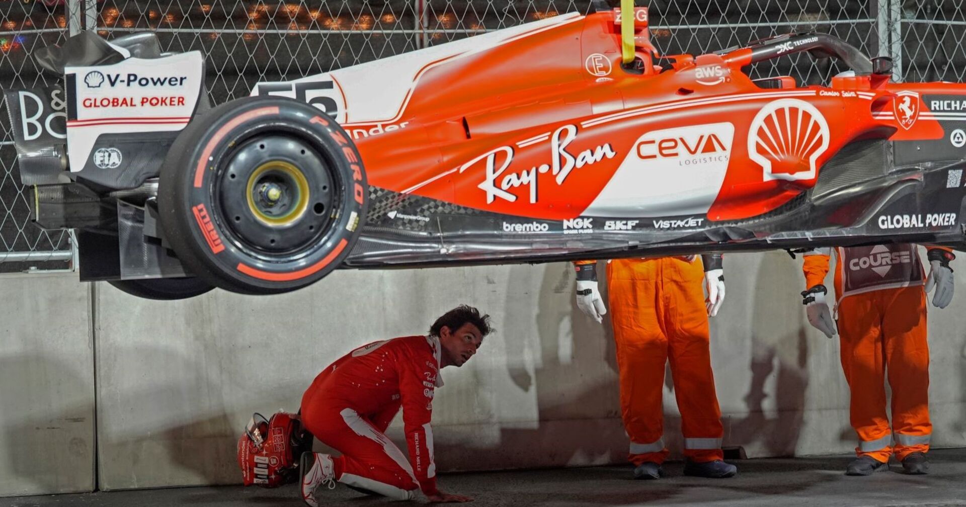 Der desolate Wagen von Ferrari wird von der Strecke gehoben. Mechaniker inspizieren den Unterboden.