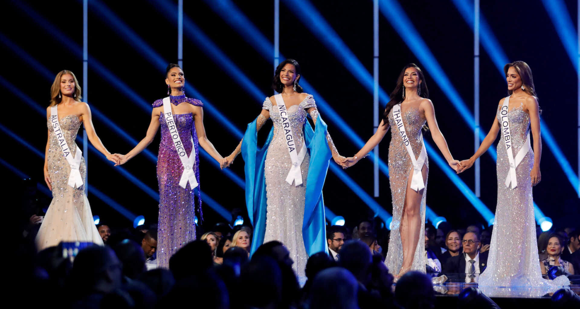 Bewerberinnen für die Miss Universe 2023 stehen auf einer Bühne in langen Abendkleidern.