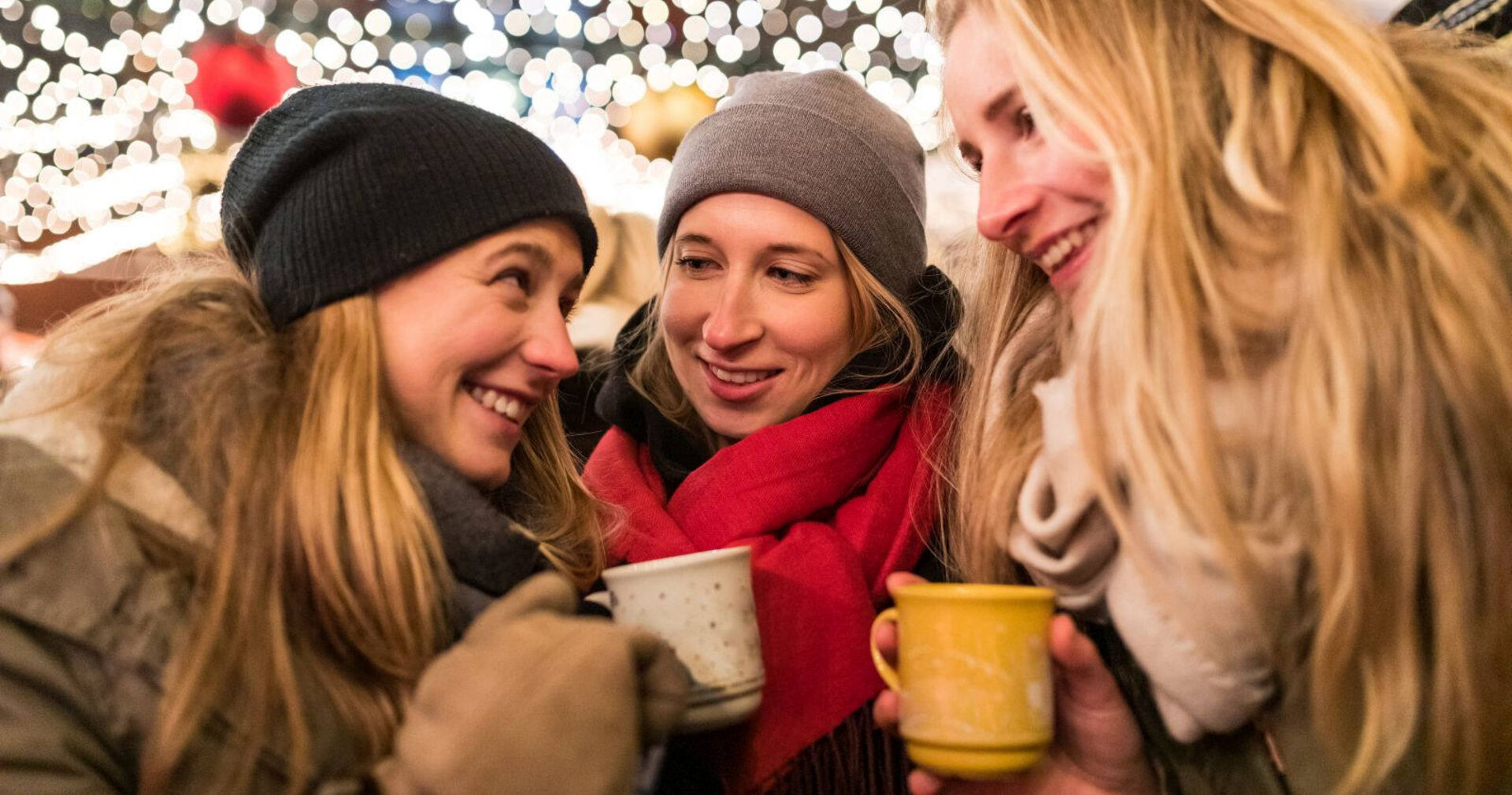 Drei Mädels trinken einen Glühwein am Christkindlmarkt.