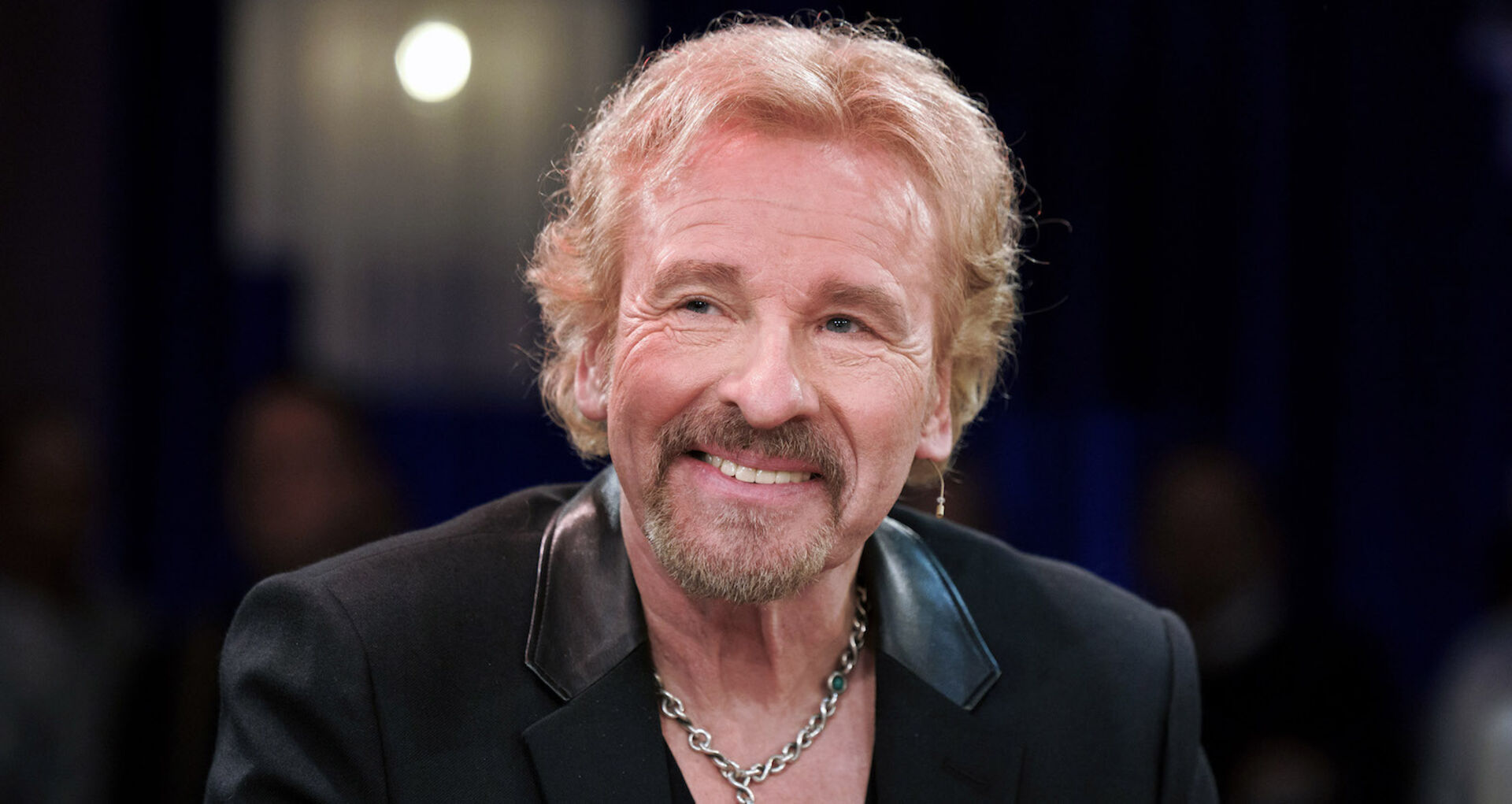Thomas Gottschalk trägt einen schwarzen Anzug und eine dicke Kette um den Hals.