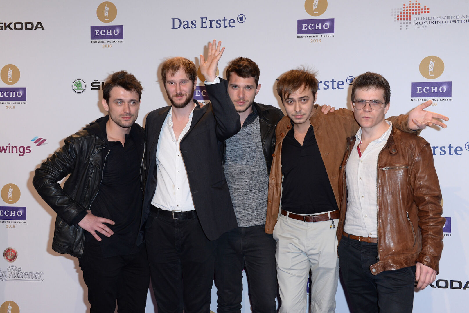 Die Band Wanda auf dem roten Teppich in alter Besetzung. Sie tragen schwarze und braune Jacken.