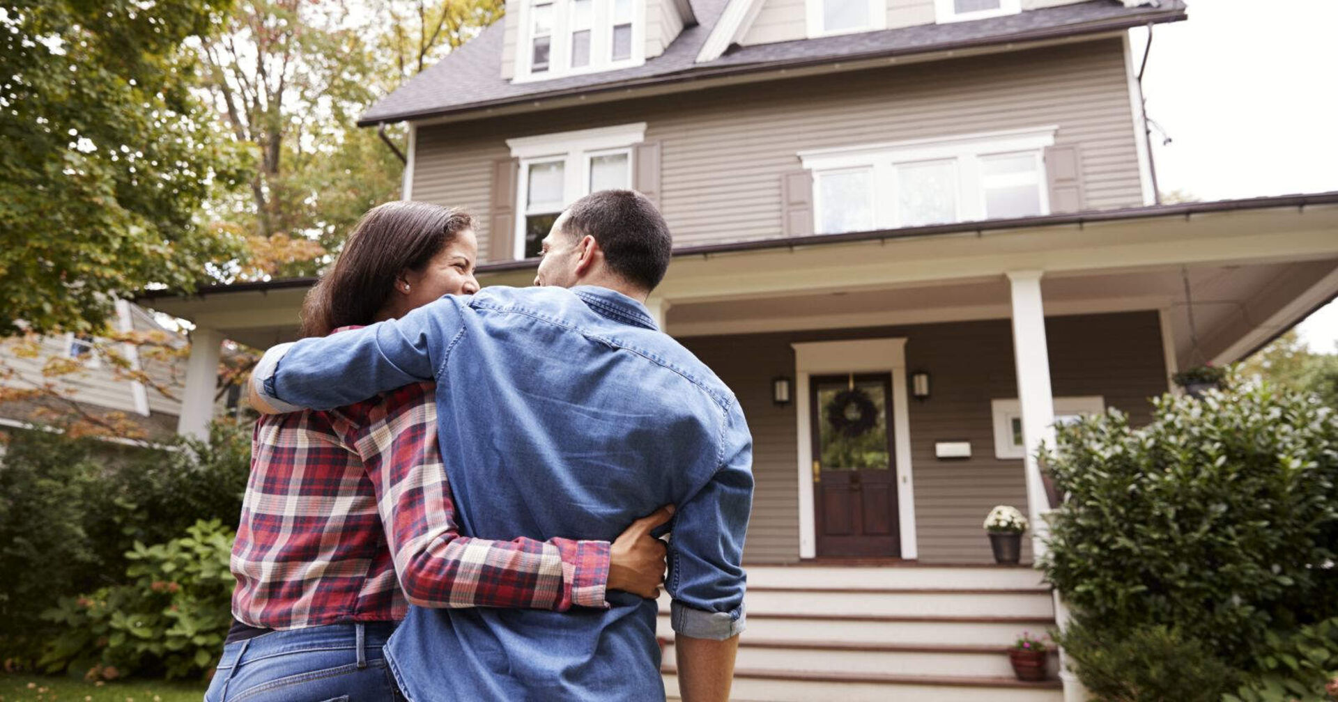 Ein Paar steht vor ihrem Haus.