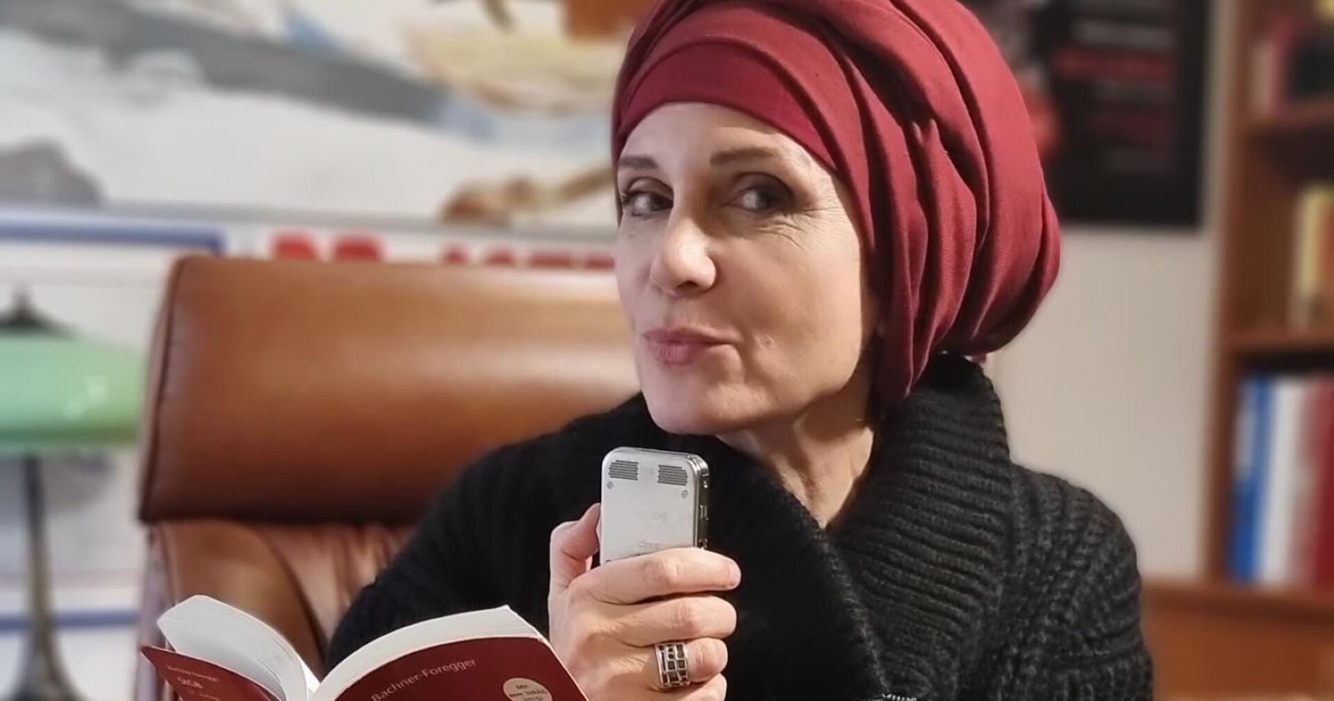 Astrid Wagner, mit Kopftuch, posiert sitzend mit Strafgesetzbuch