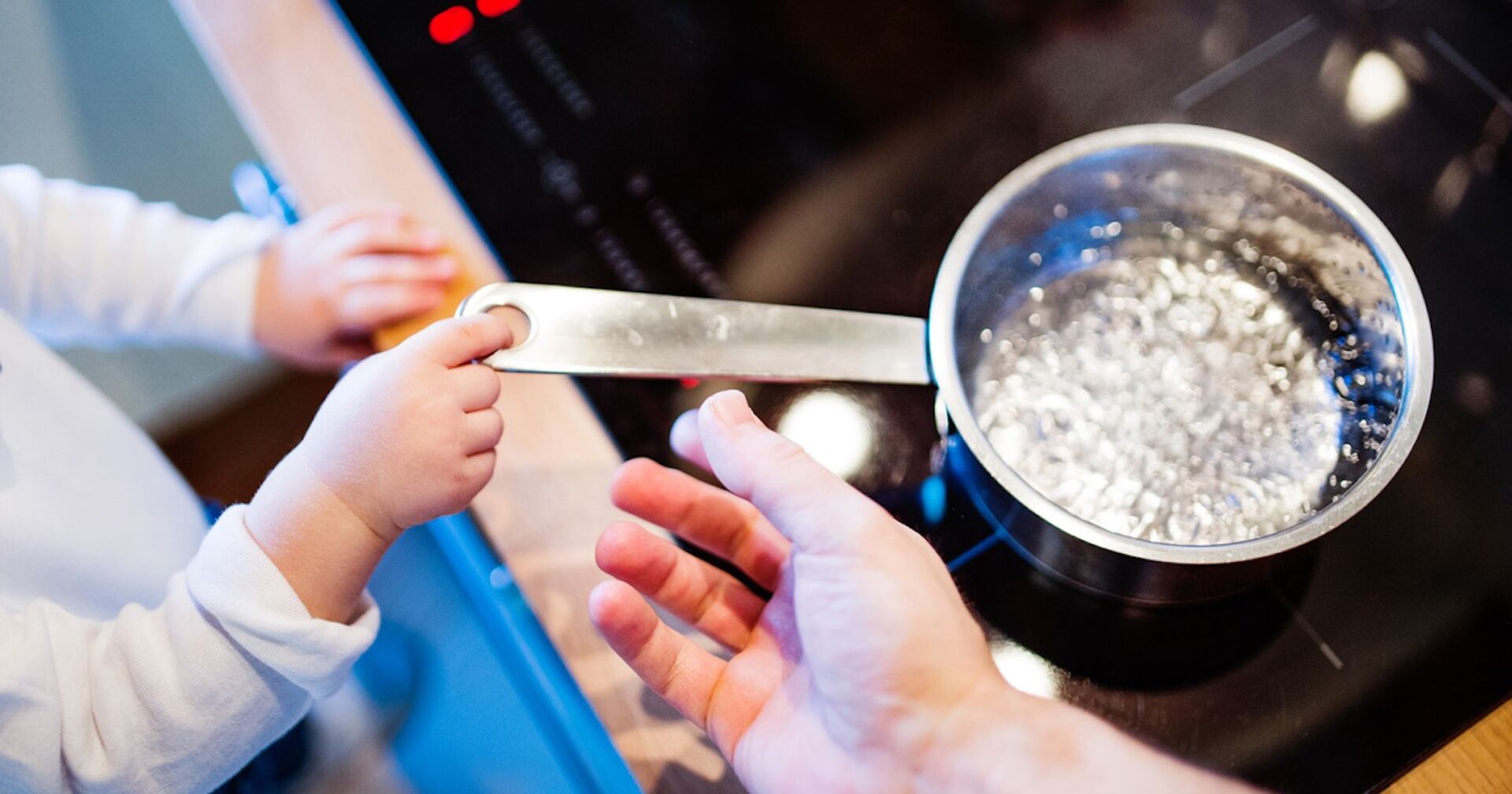 Ein Kind greift nach einem Topf mit kochend heißem Wasser.