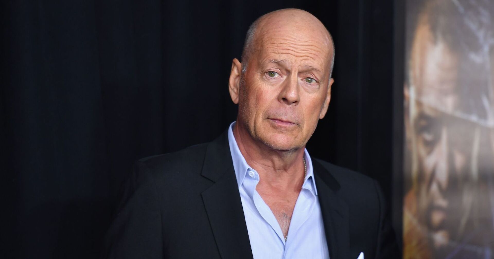 Bruce Willis mit einem dunkelblauen Sakko und einem hellblauen Hemd.