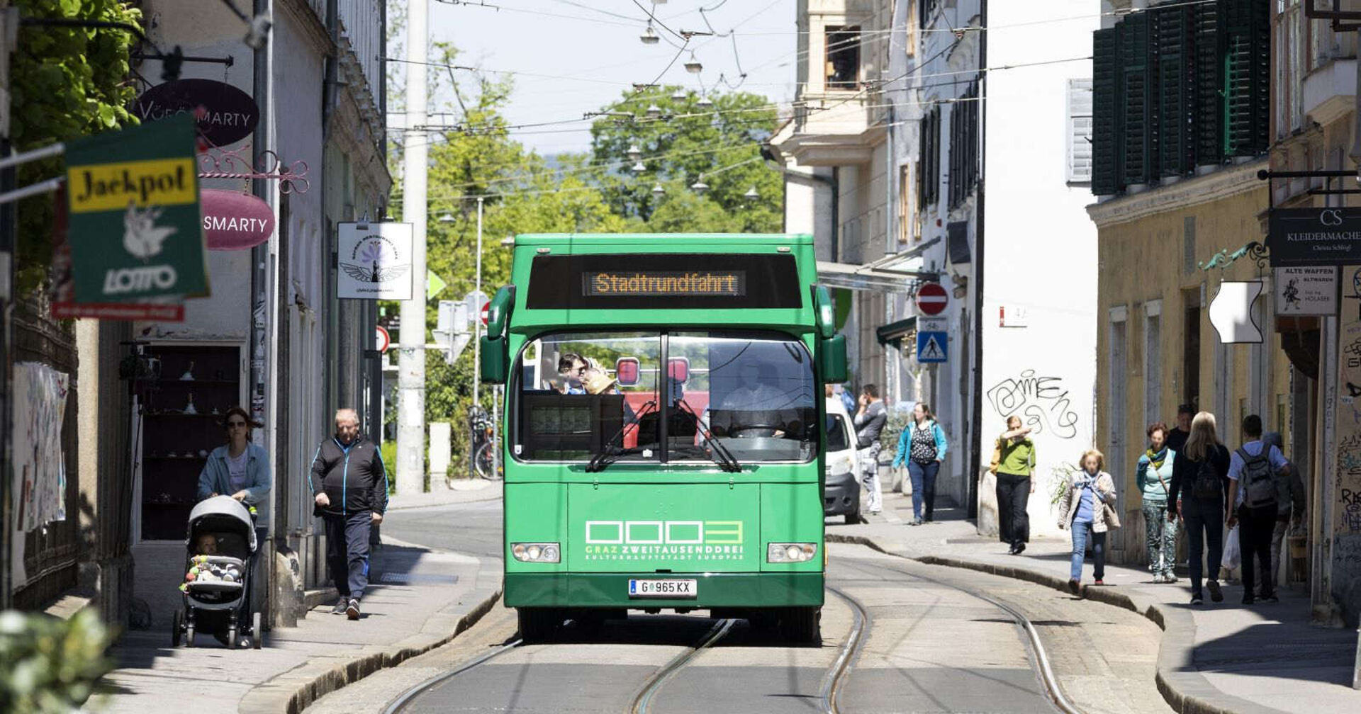 Ein grüner Bus fährt durch Graz.