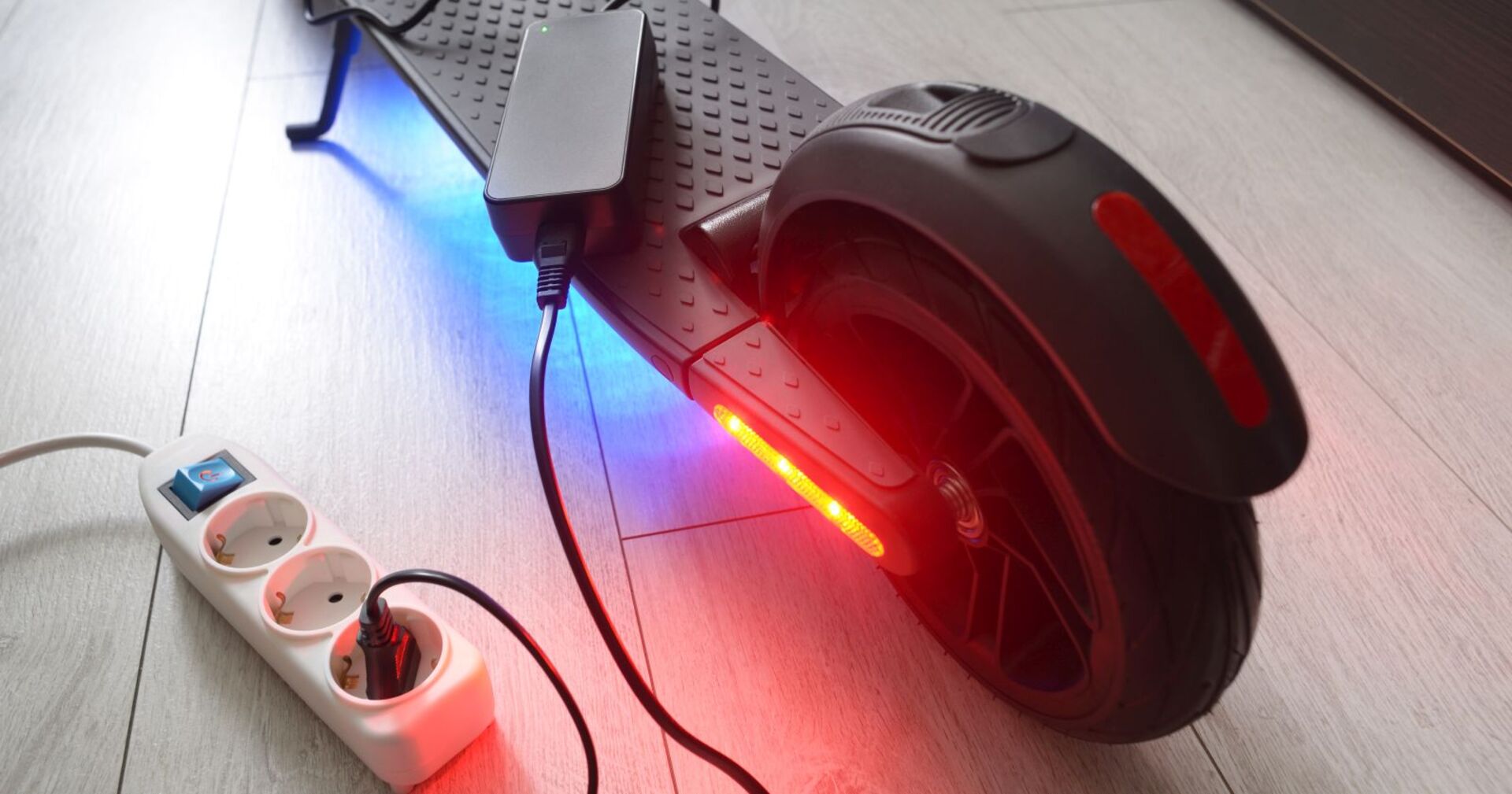 Ein E-Scooter wird an einer Steckdose aufgeladen.