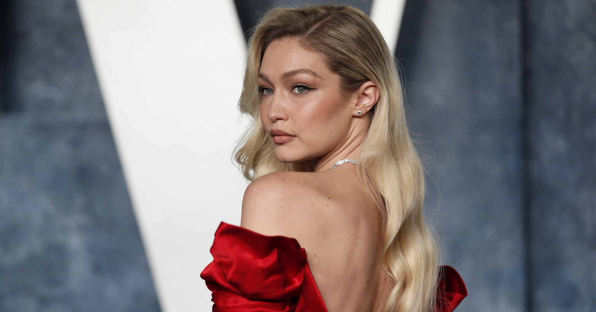 Gigi Hadid schaut über die Schulter. Sie trägt offene blonde Haare und ein rotes Kleid.