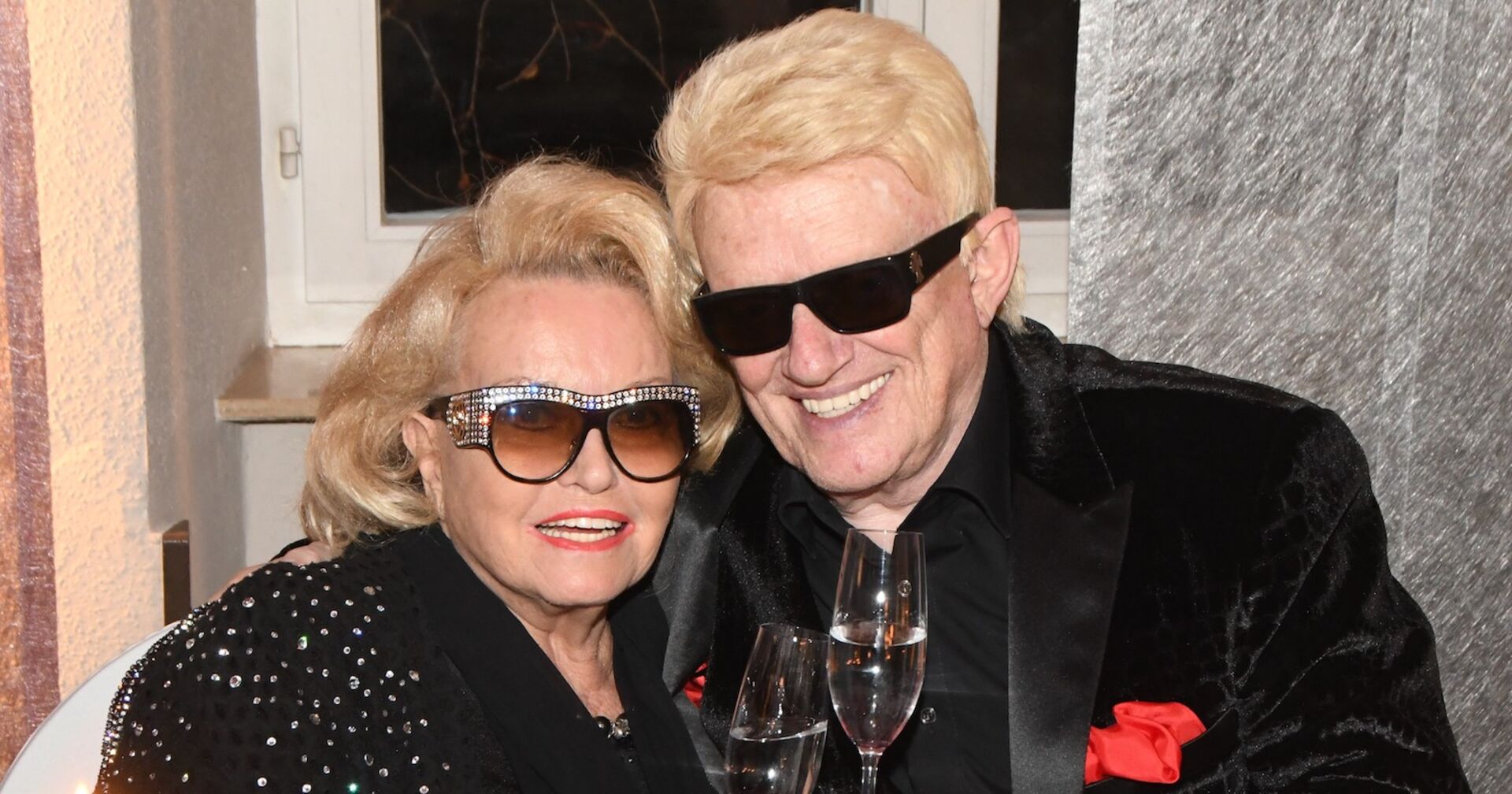 Heino und Hannelore mit blonden Haaren, Sonnenbrillen und Sektgläsern.