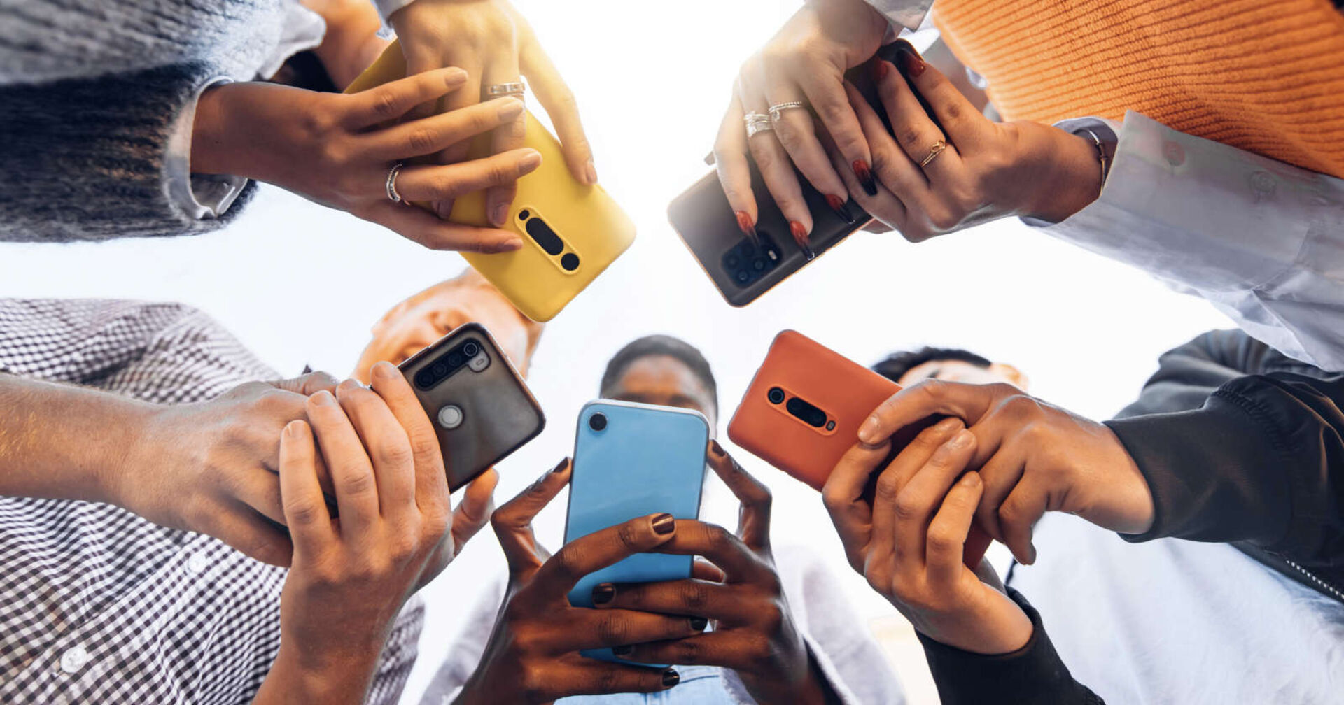 Jugendliche halten ihr Handy in der Hand.