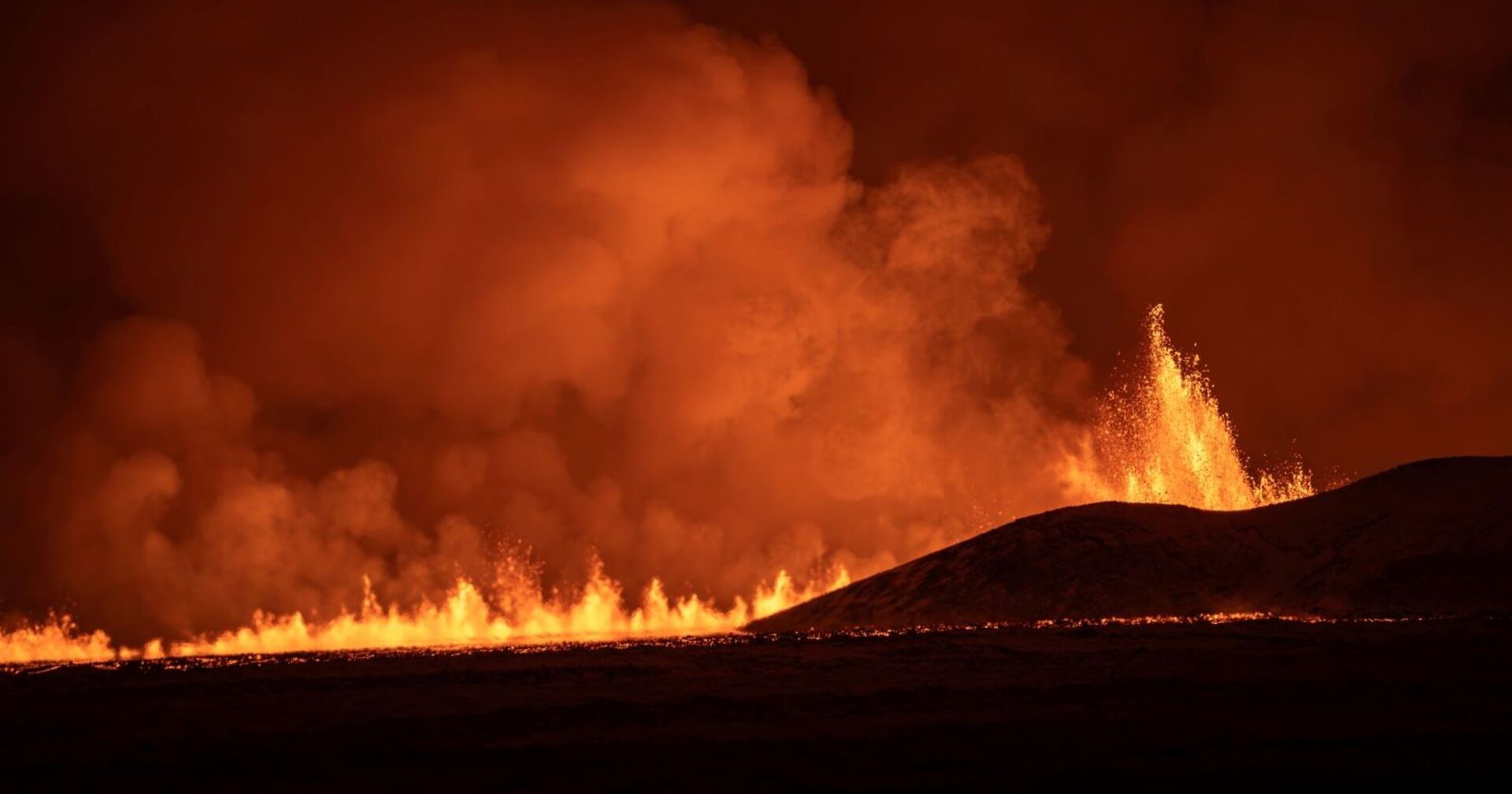 Ein Riss in der Erde aus dem Lava in einer Fontäne in den dunklen Himmel schießt