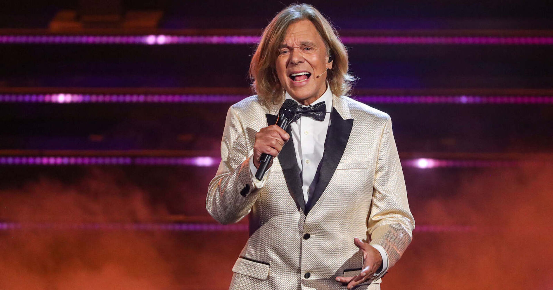 Jürgen Drews auf der Bühne mit einem silbernen Sakko und einem Mikrofon.