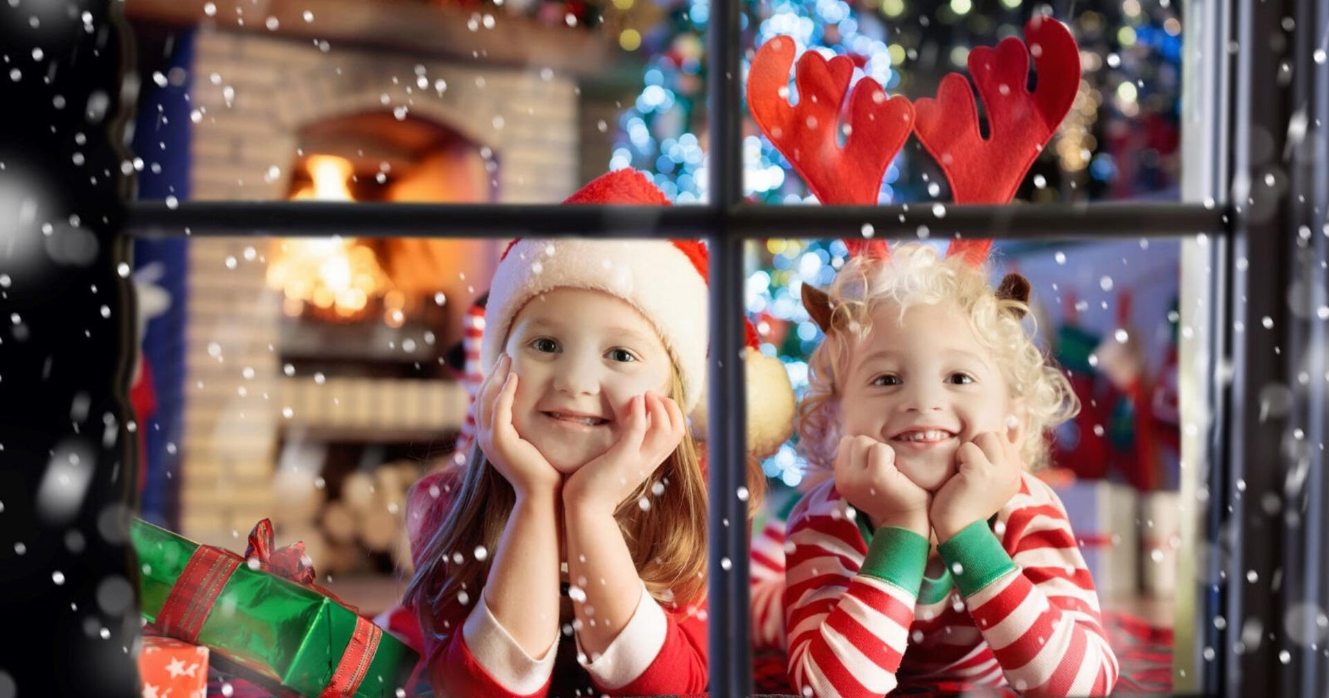 Zwei Kinder blicken gespannt aus dem Fenster