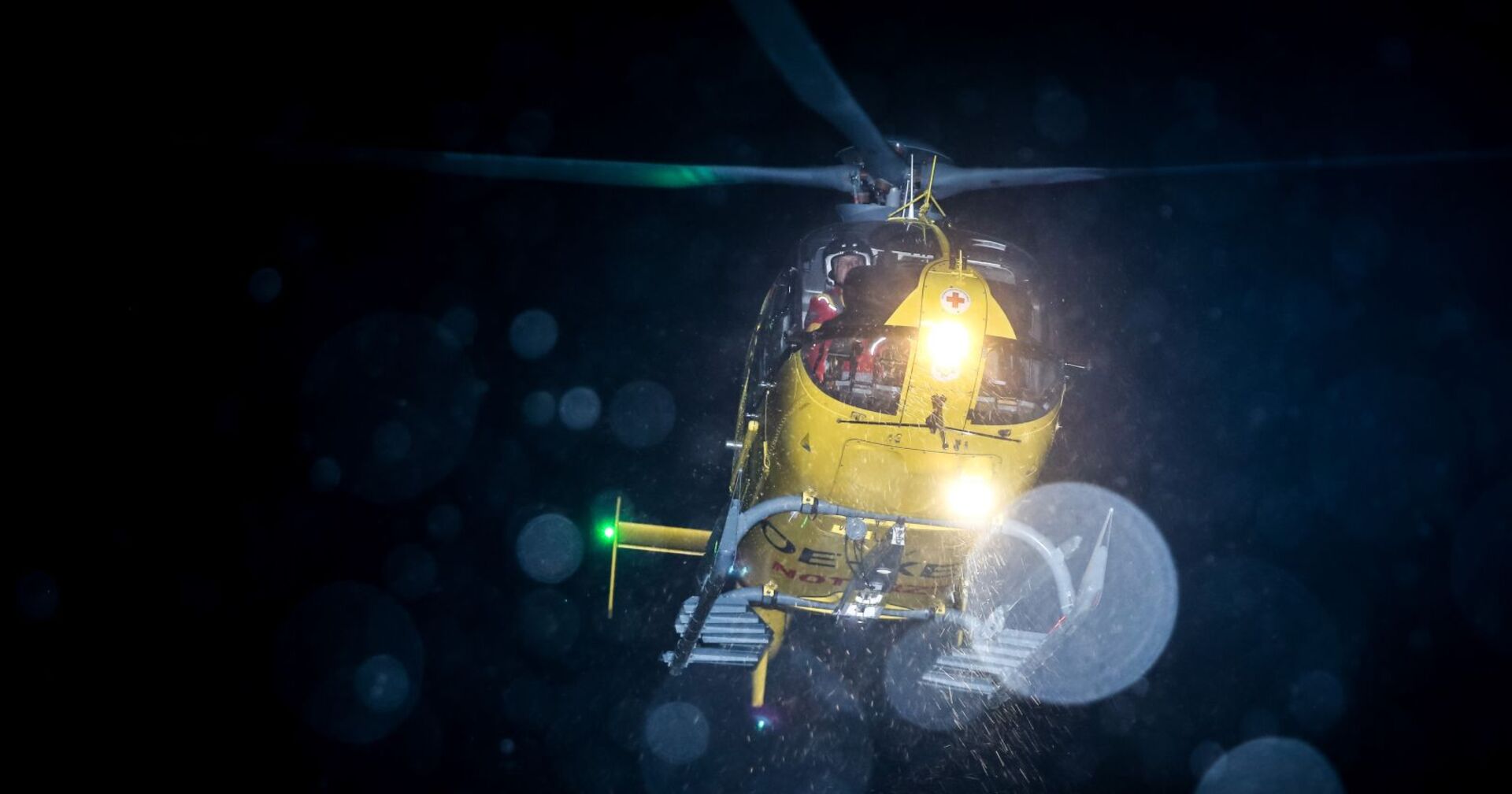 Ein gelber Rettungshubschrauber im nächtlichen Einsatz.