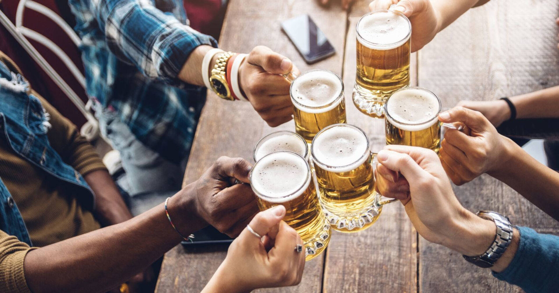 Freunde stoßen mit einem Bier an.