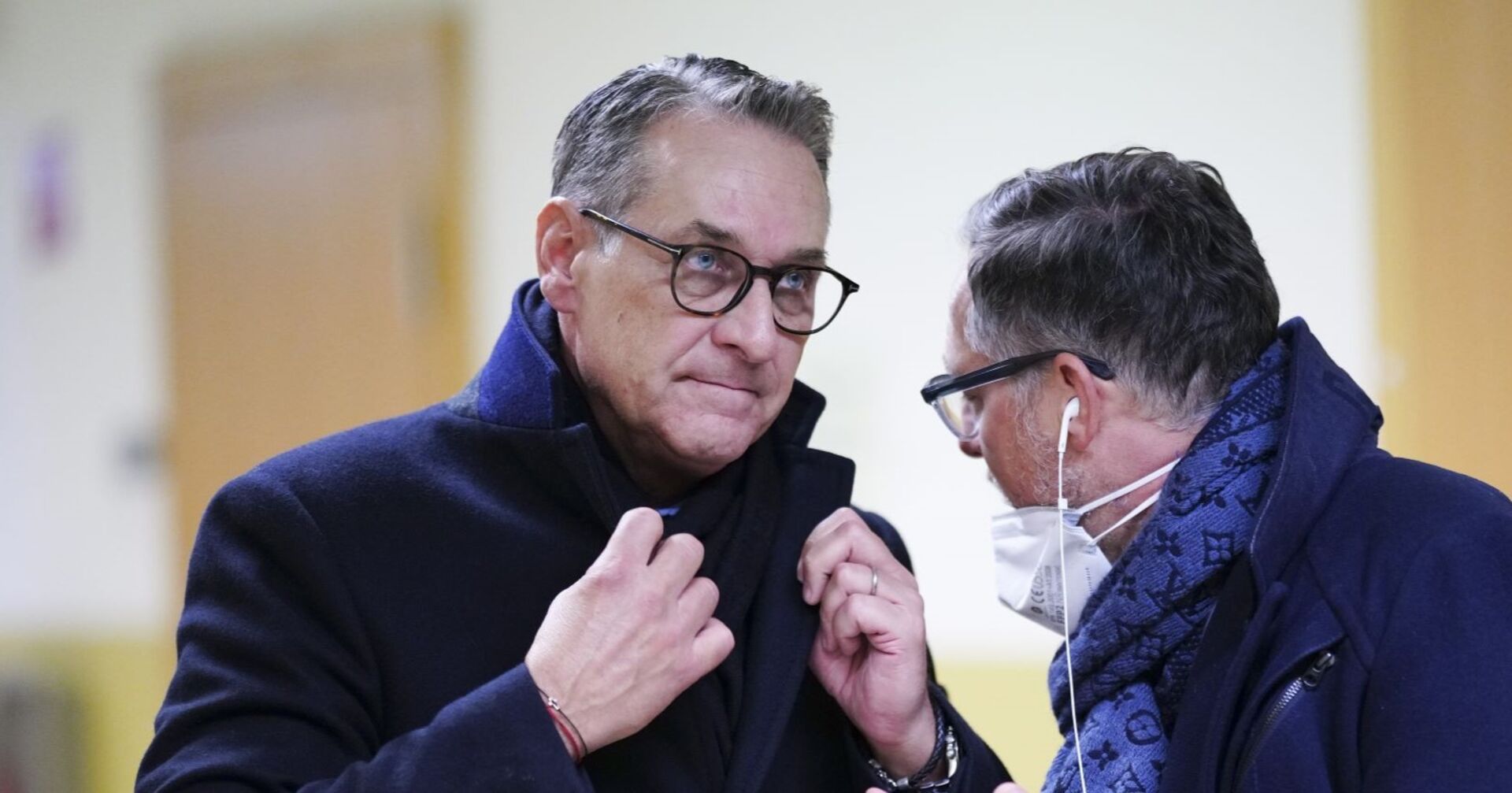 HC Strache im Wintermantel richtet seinen Schal, im Gespräch, er hört zu.