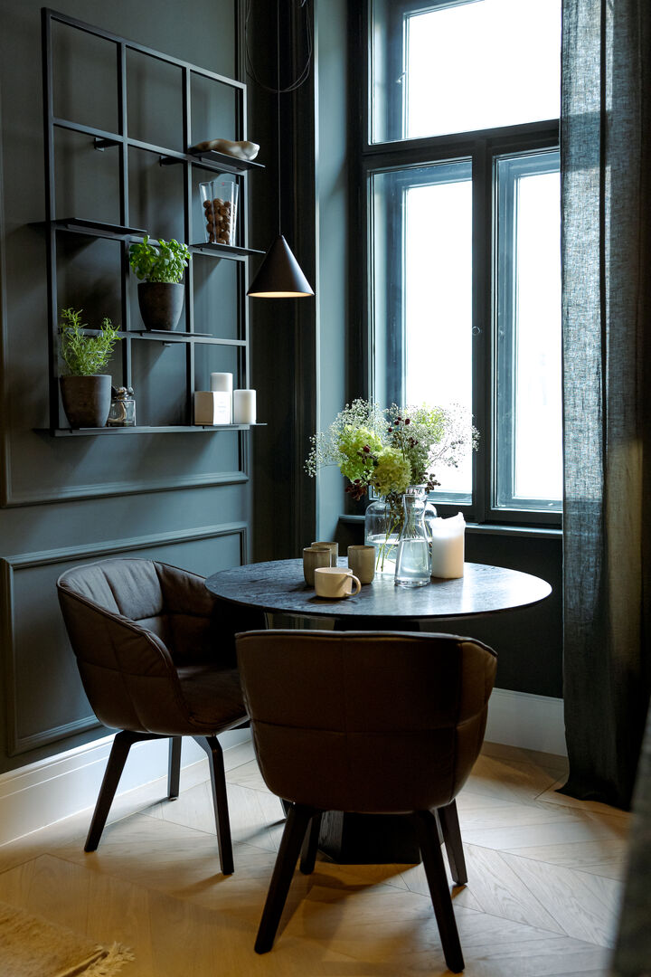 Ein runder Tisch mit zwei Stühlen und einem dunklen Wandregal