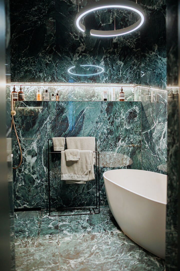 Grüner Marmor an der Wand und eine runde Badewanne