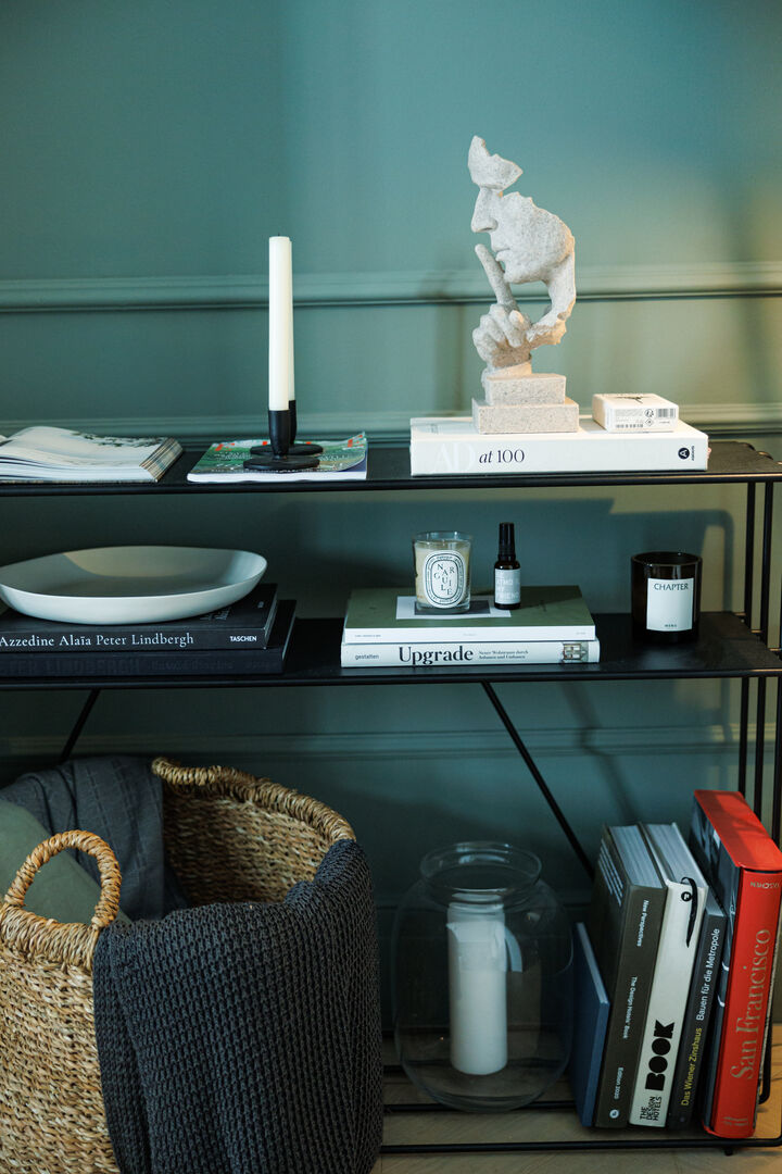 Ein Regal mit Büchern, Deko, Kerzen und einem Korb