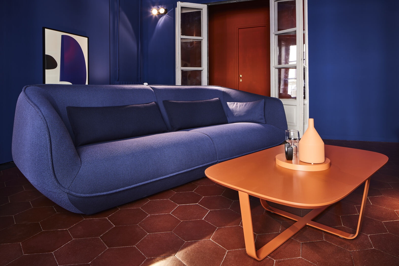 Blaue Couch in blauem Raum vor orangem Beistelltisch