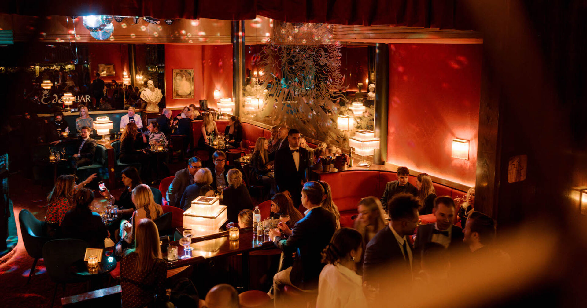 Blick in die abendlich beleuchtete Bar mit Gästen