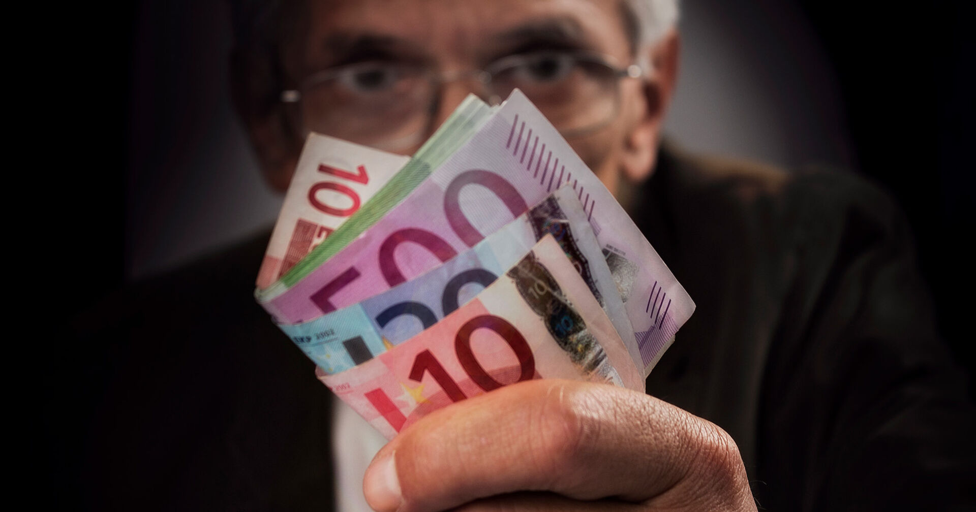 Mann mit mehreren Euro-Scheinen in der Hand.