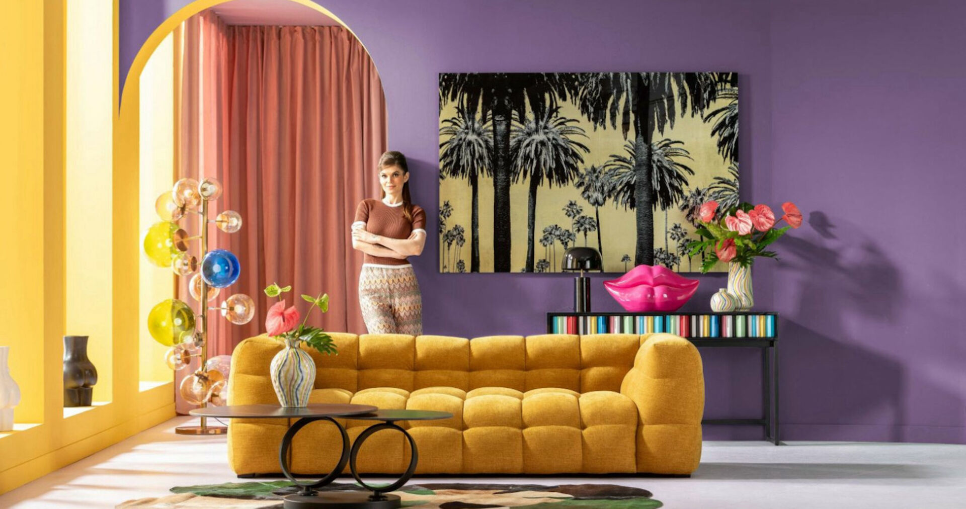 Wohnzimmer mit senffarbener Couch, lila wand, Frau im Hintergrund