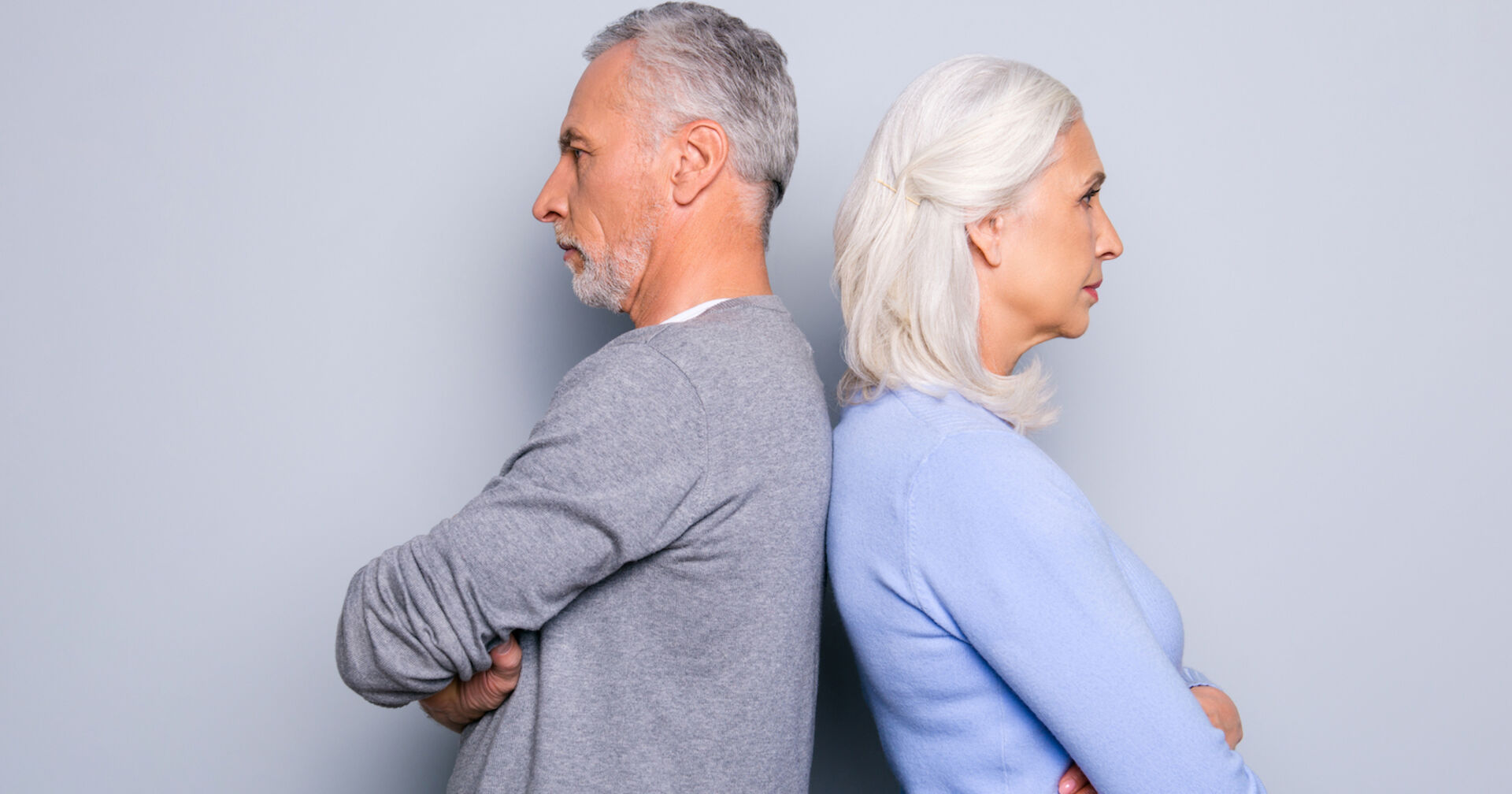 Ein unglückliches, älteres Paar steht Rücken an Rücken