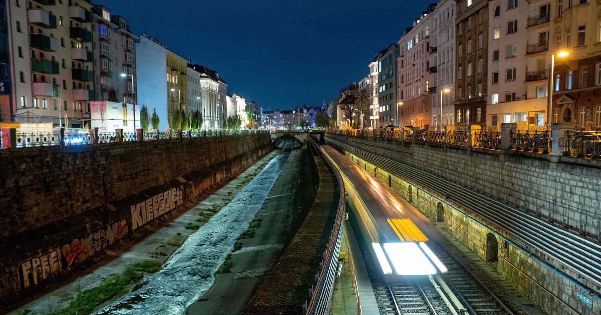 Blick auf den nächtlichen Wienfluss und die neben dem Kanal fahrende Ubahn