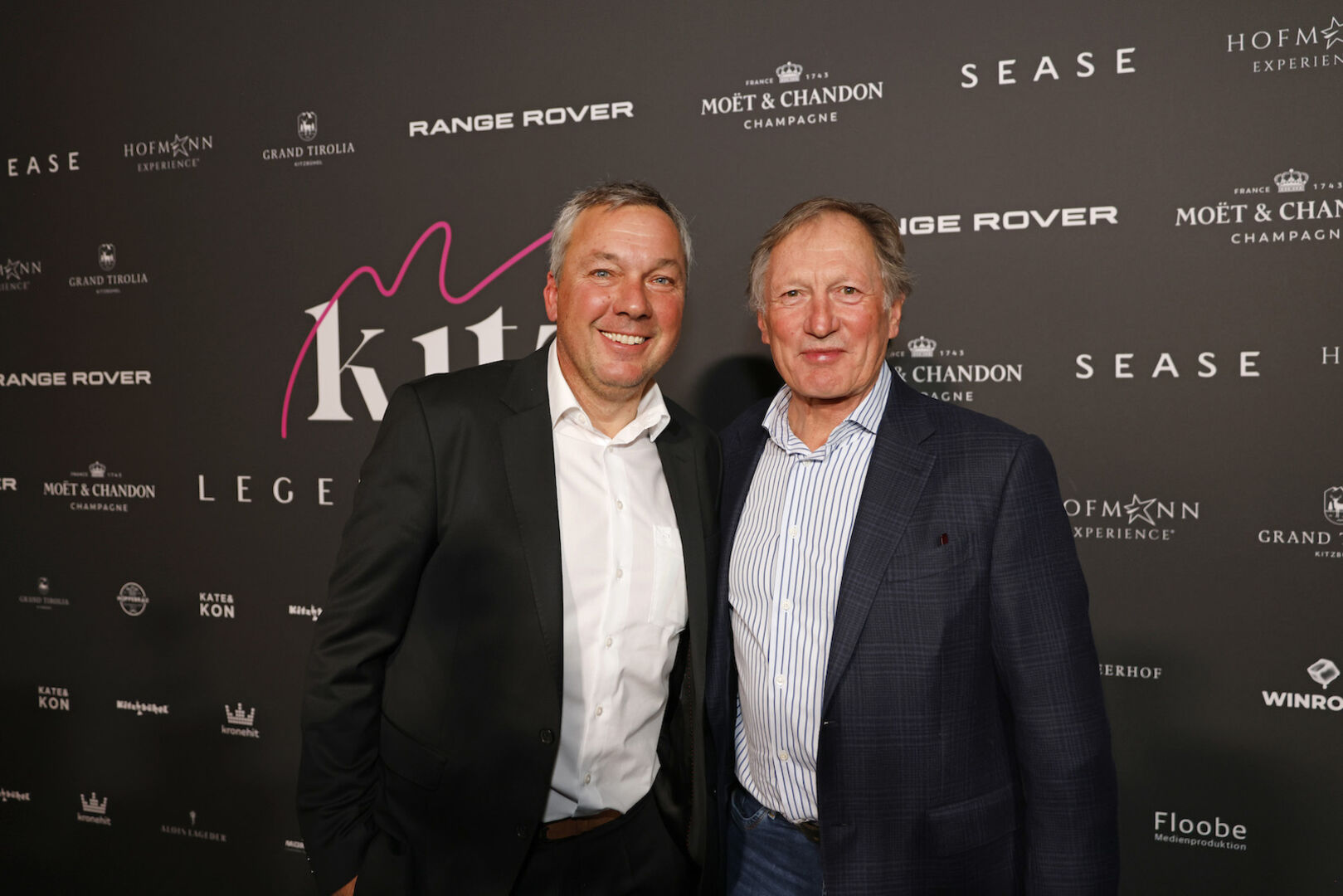 Fritz Strobl und Franz Klammer vor einer Fotowand.