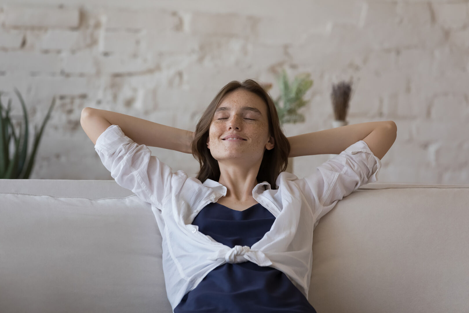 Frau sitzt entspannt am Sofa | Credit: iStock.com/fizkes