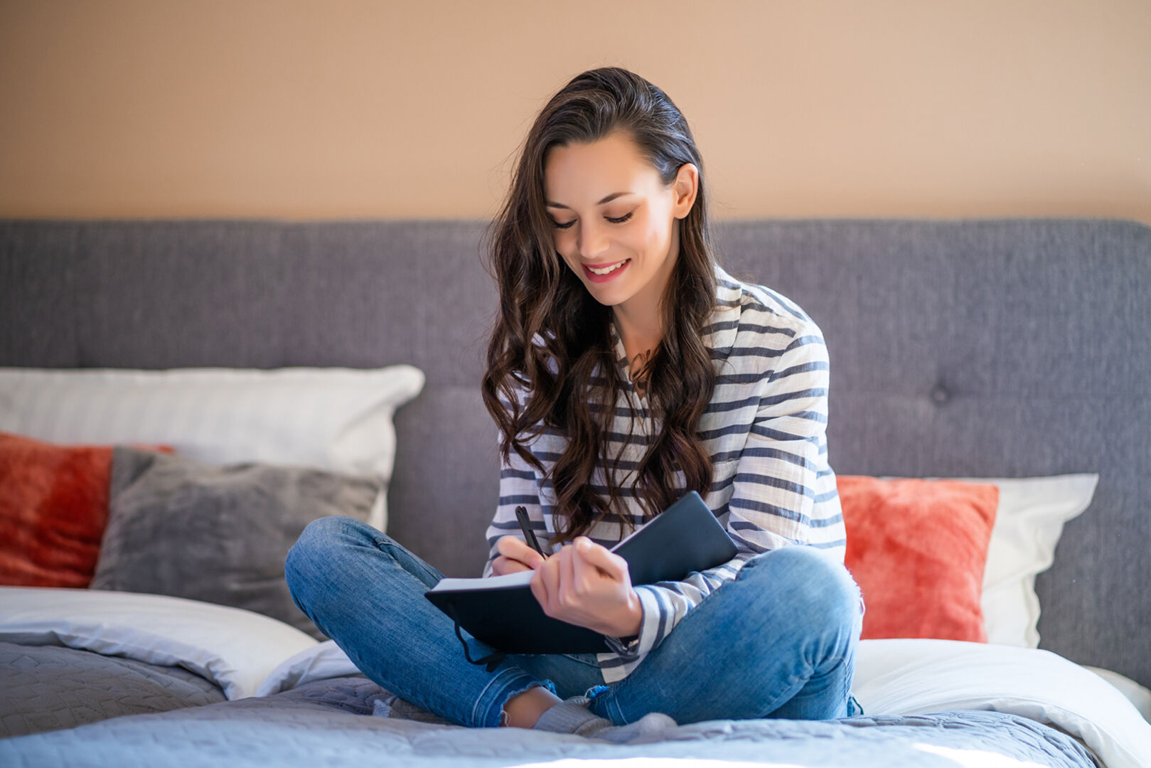 Frau schreibt Tagebuch am Bett | Credit: iStock.com/Photodjo