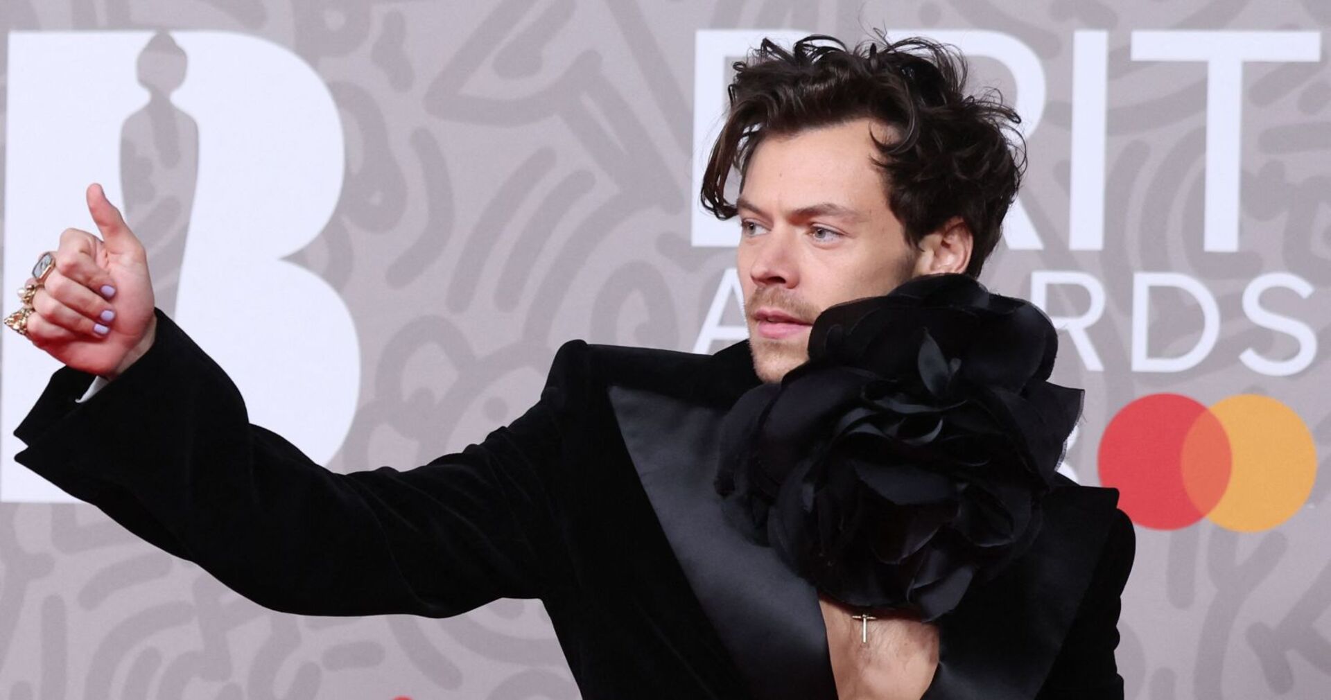 Harry Styles zeigt auf einem Event &quot;Daumen hoch&quot;.