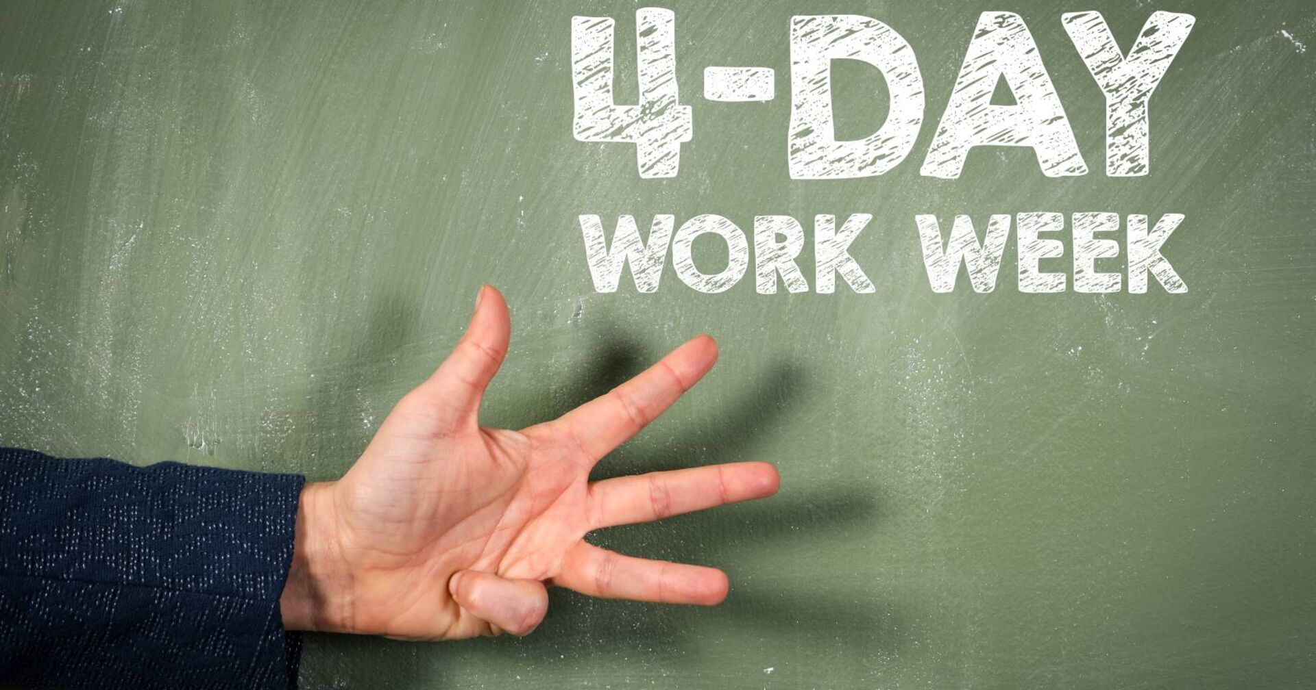 Eine Hand mit vier ausgestreckten Fingern vor einer Tafel mit der Aufschrift: 4-Day Work Week