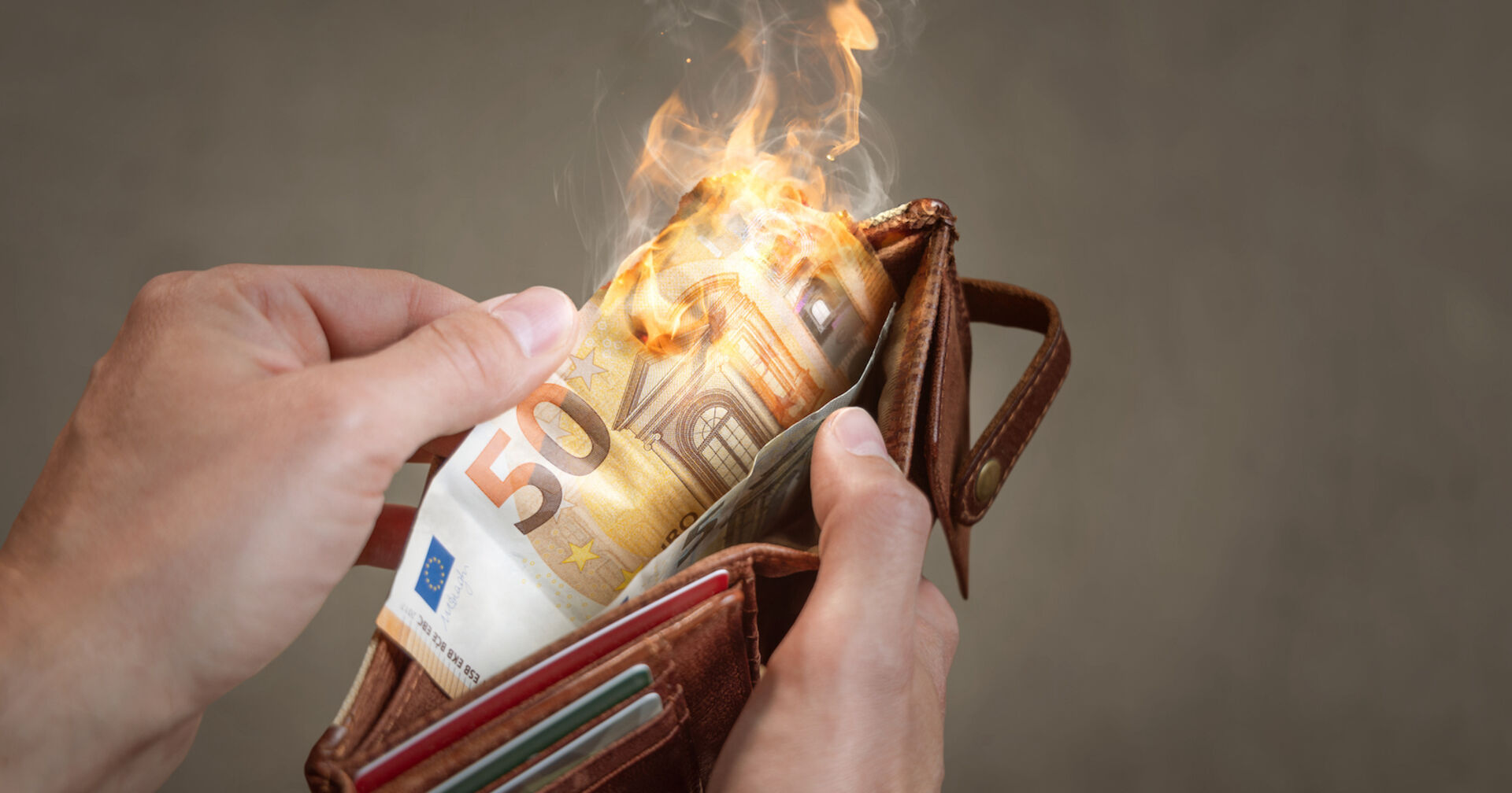 Eine Mann öffnet eine Geldtasche. Der 50-Euro-Schein darin brennt