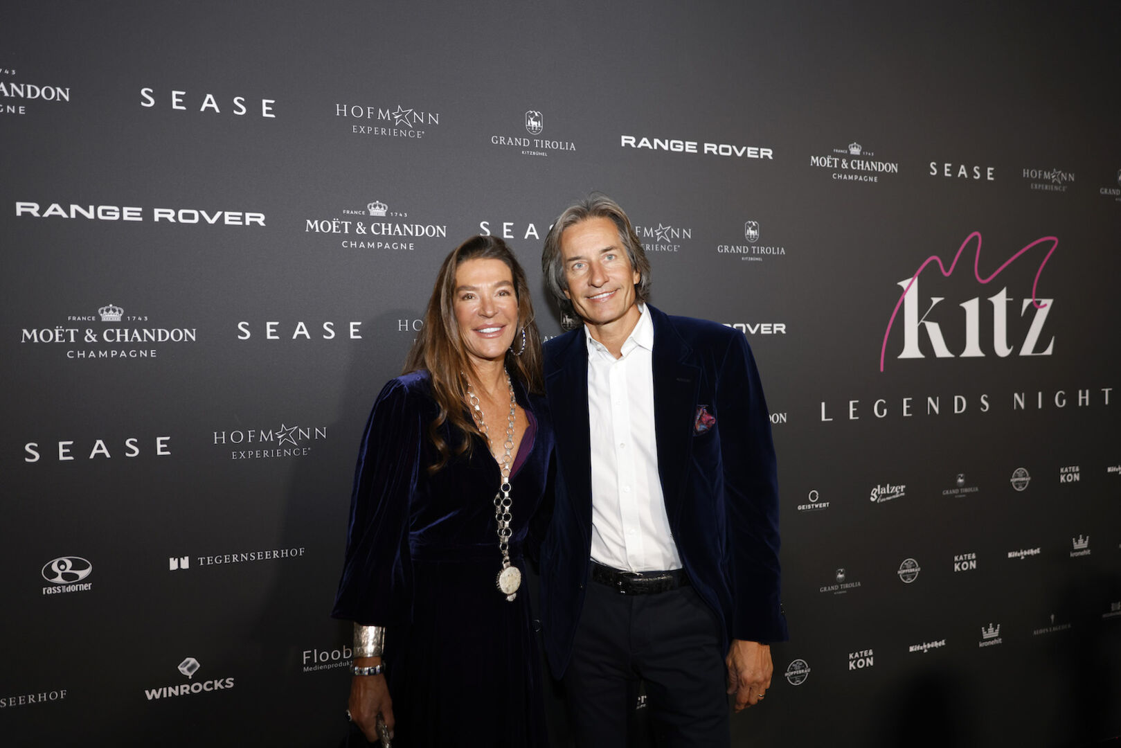 Fiona Swarovski und Karl Heinz Grasser vor einer Fotowand.