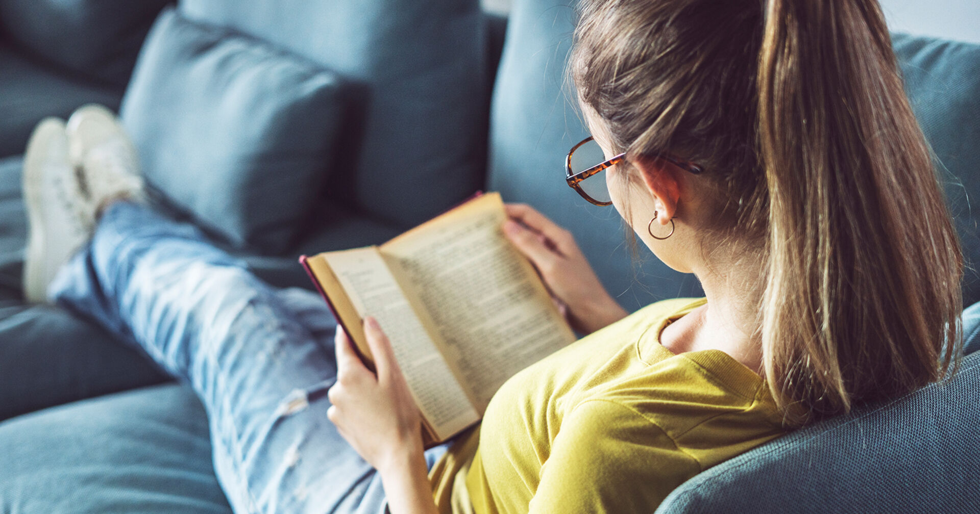 Frau liest ein Buch am Sofa | Credit: iStock.com/seb_ra