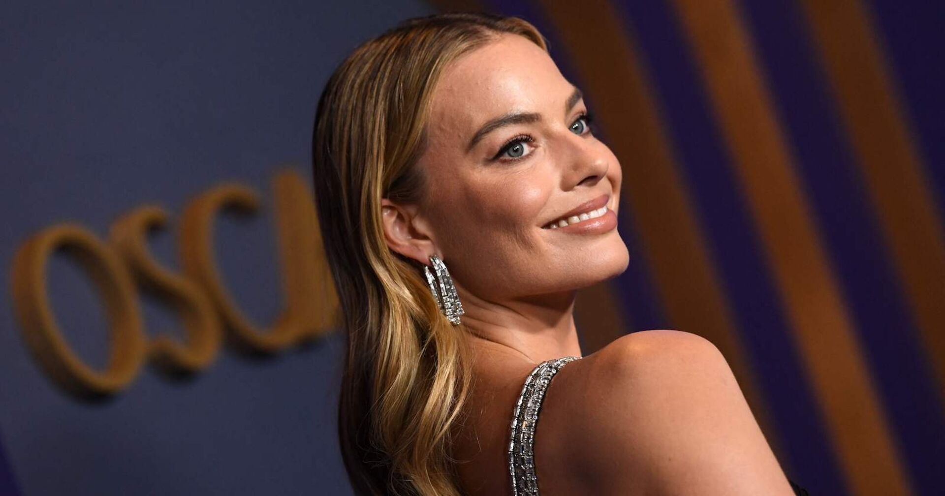 Margot Robbie bei den Oscars. Sie trägt offene blonde Haare und Diamantenohrringe.