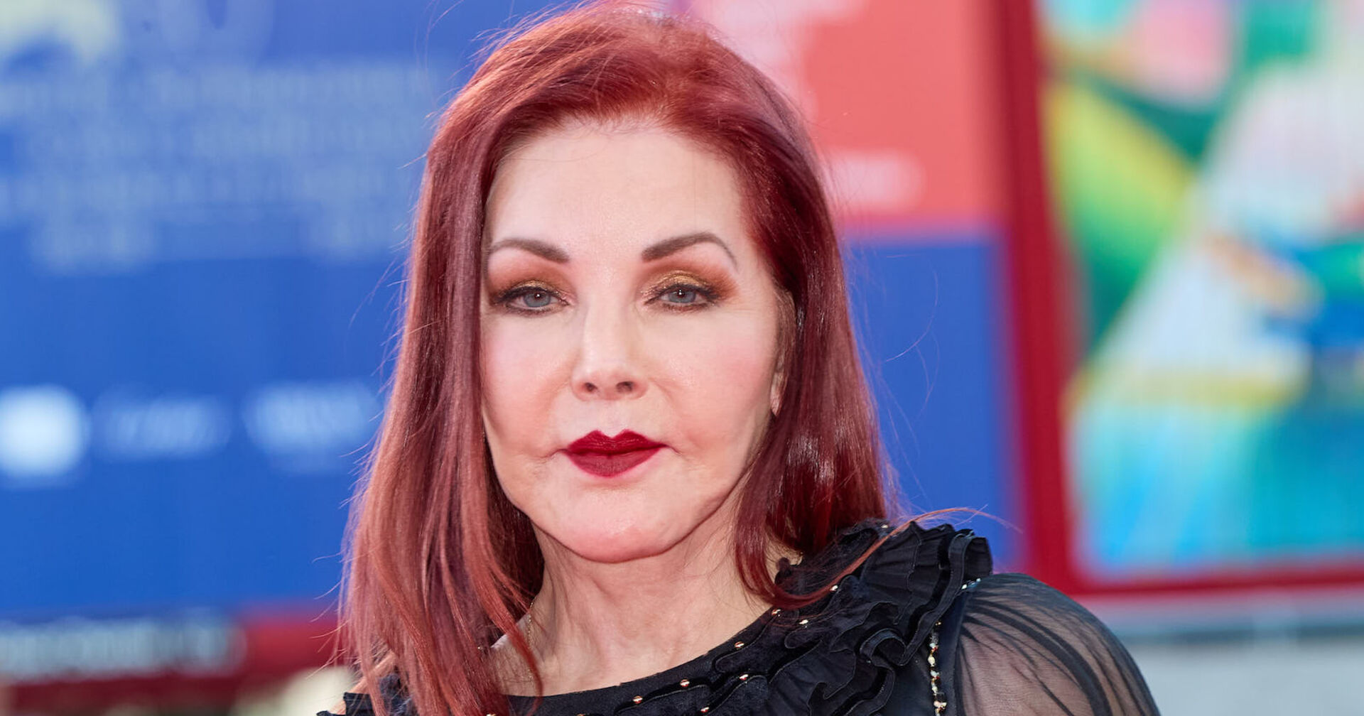 Priscilla Presley mit roten, offenen Haaren und roten Lippenstift.