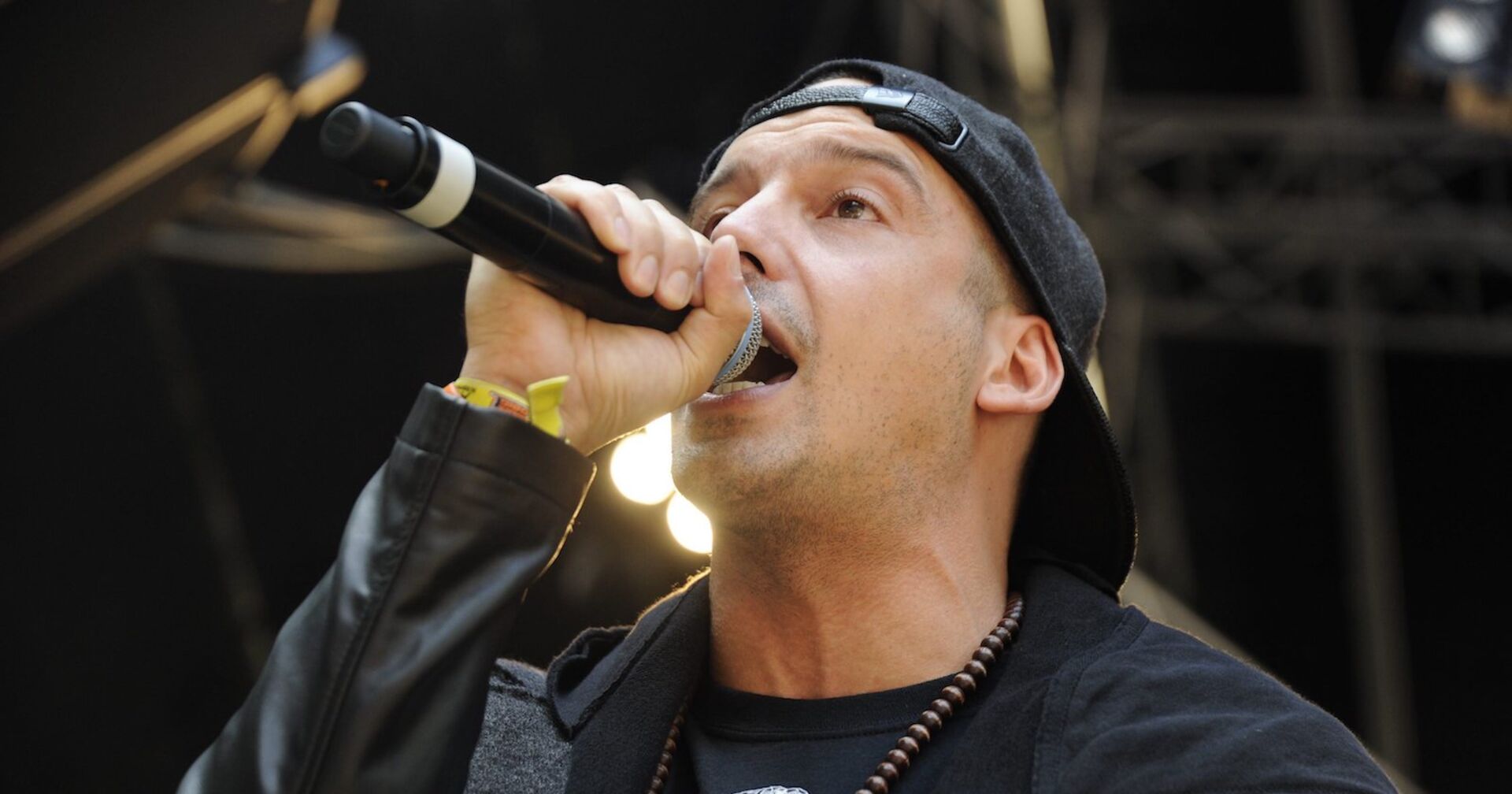 Raf Camora mit einem Mikrofon auf der Bühne. Er trägt eine Kappe.