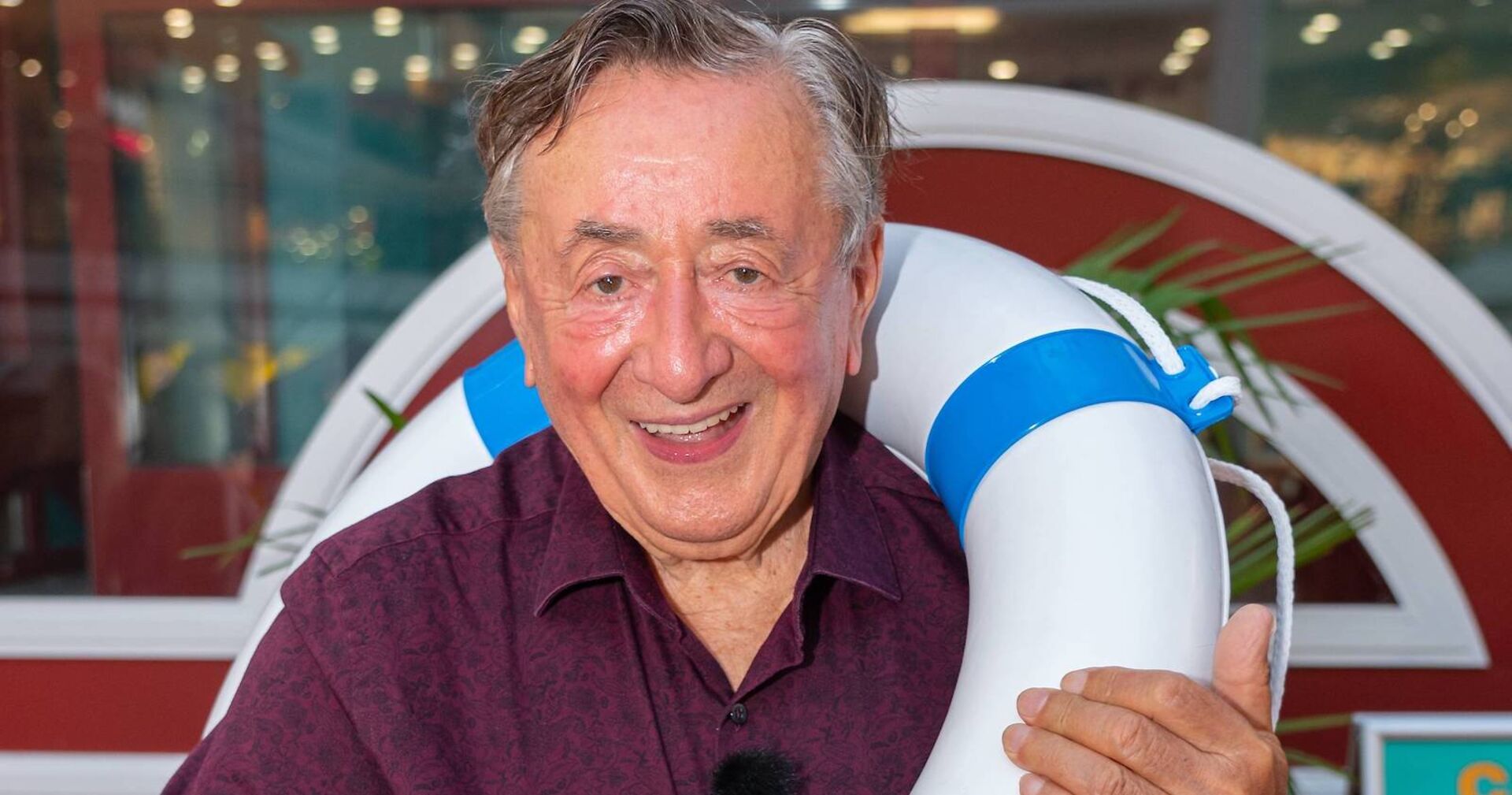 Richard Lugner mit einem dunkelroten Hemd und einem Rettungsreifen.