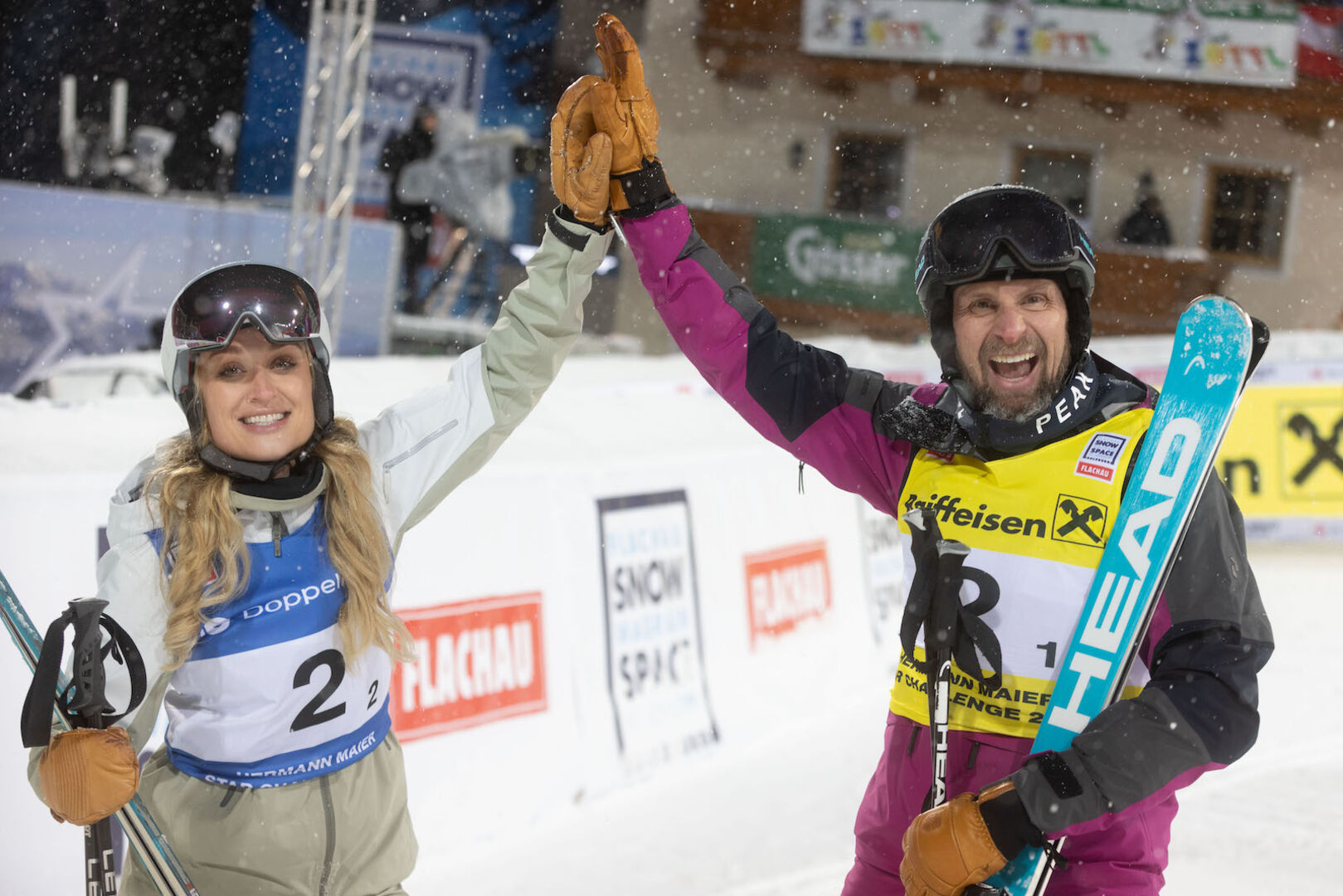Marco Büchel und Rennfahrerin Corinna Kamper halten die Hände zum Jubeln hoch.